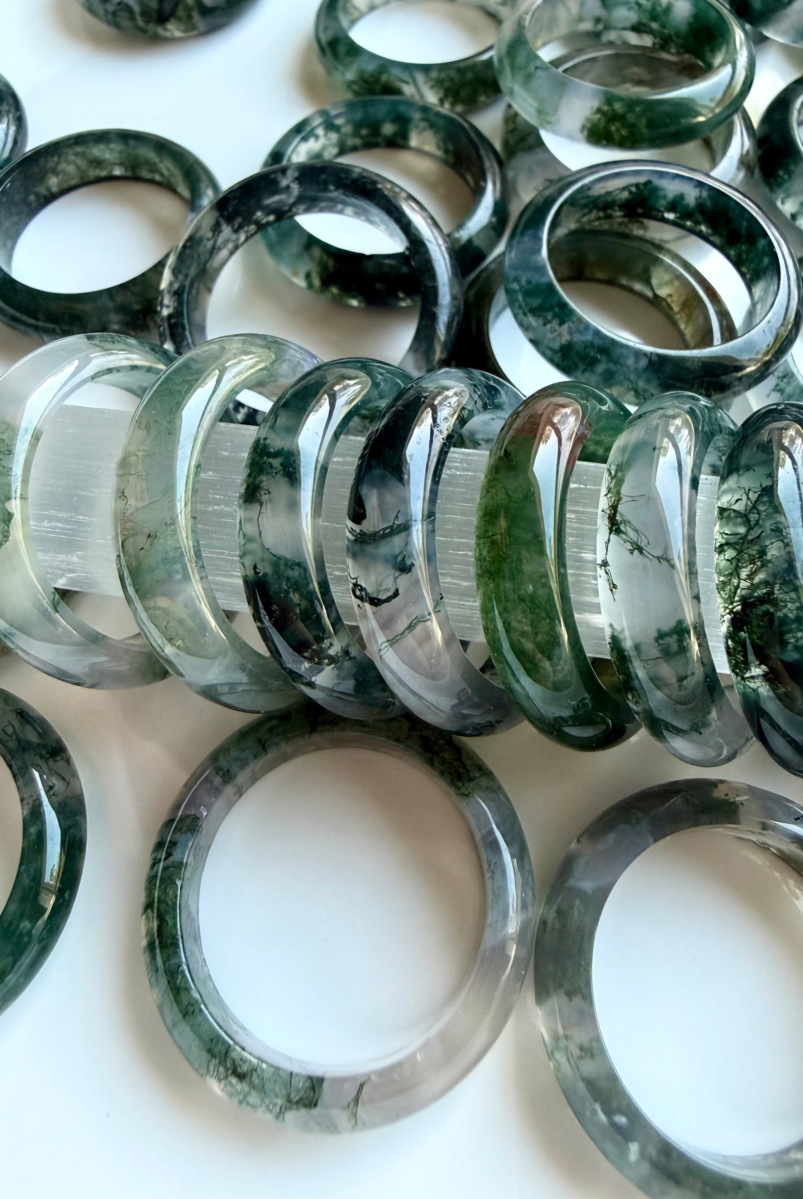collection of moss agate rings in soft lighting highlighting translucency and inclusions, healing crystal jewelry for calm and grounding
