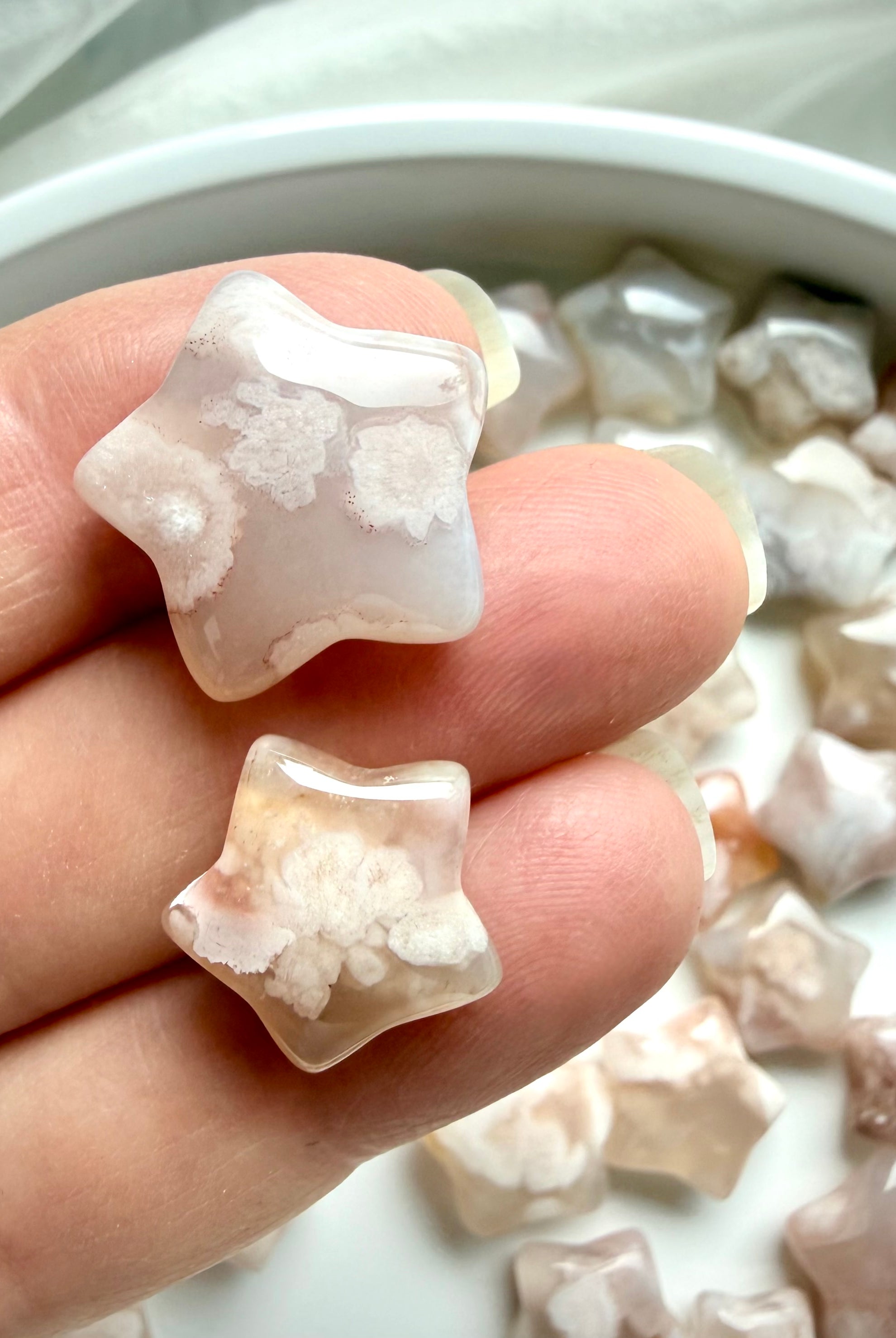 Close up of two mini Flower Agate star carvings with floral patterns and dreamy pastel chalcedony tones