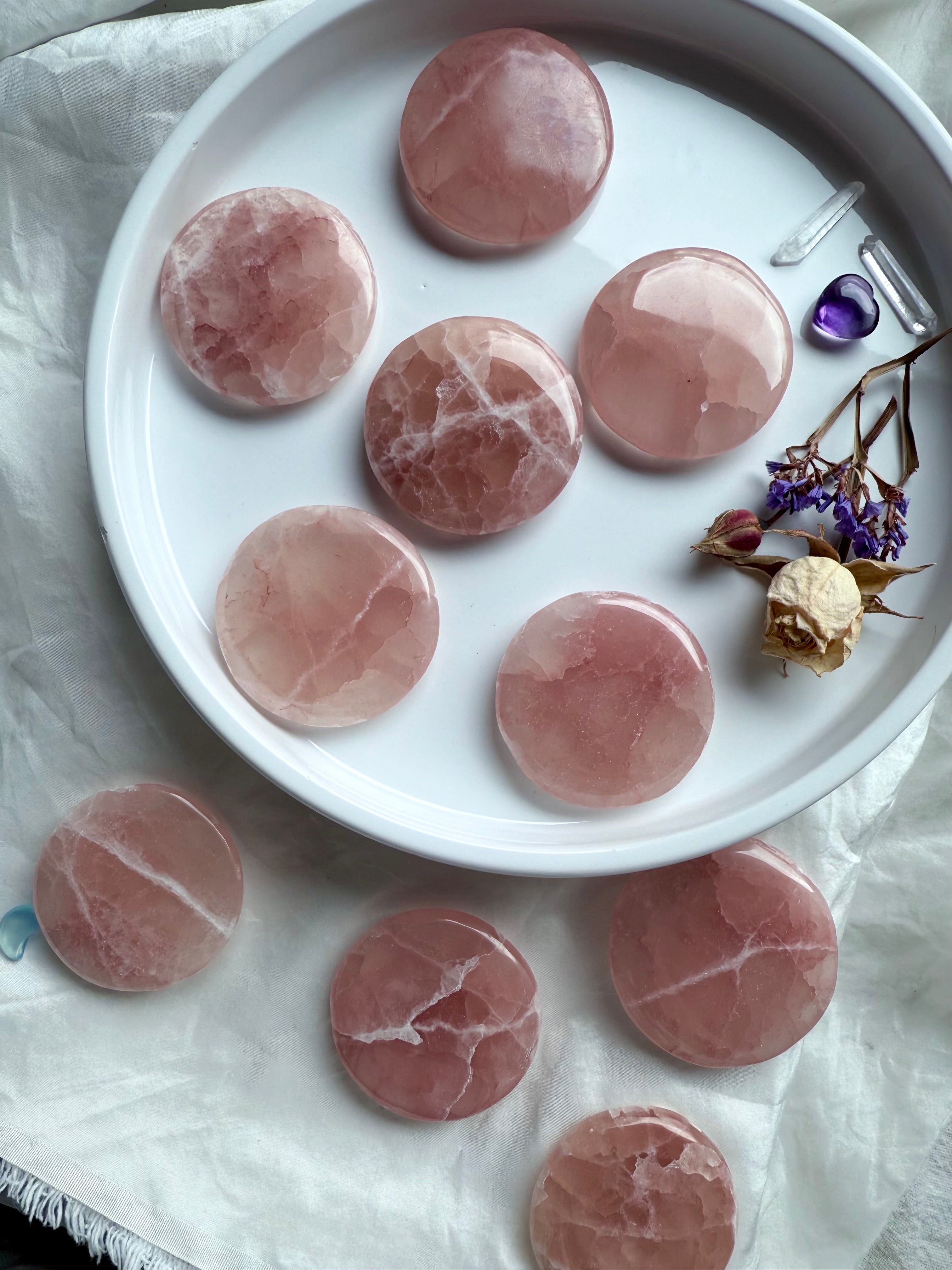 Assortment of polished rosey Pink Calcite crystals arranged around a white dish with amethyst and quartz