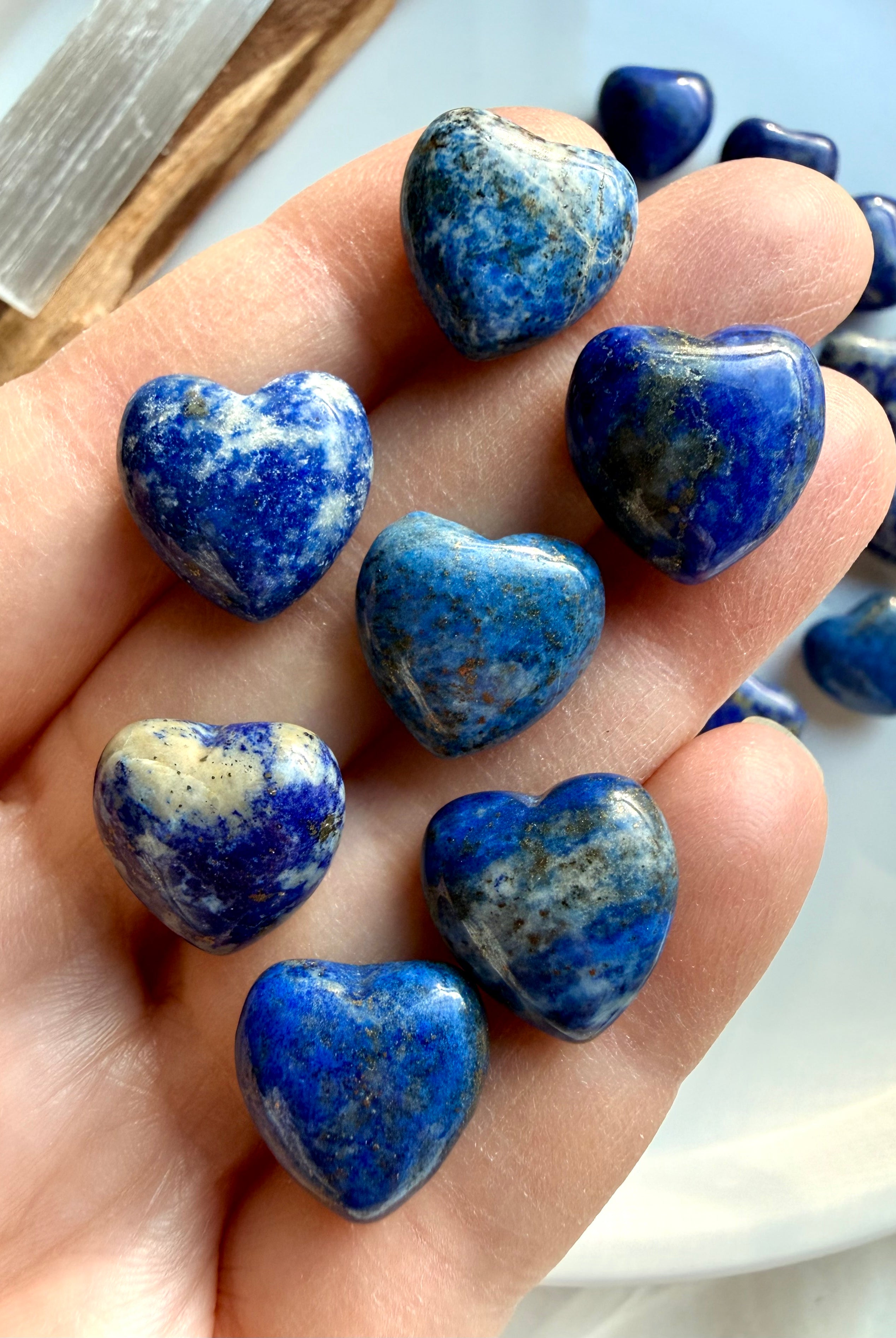 Mini Lapis Lazuli heart crystals resting in hand, polished blue stone hearts with natural calcite patterns, small pocket-size healing crystals