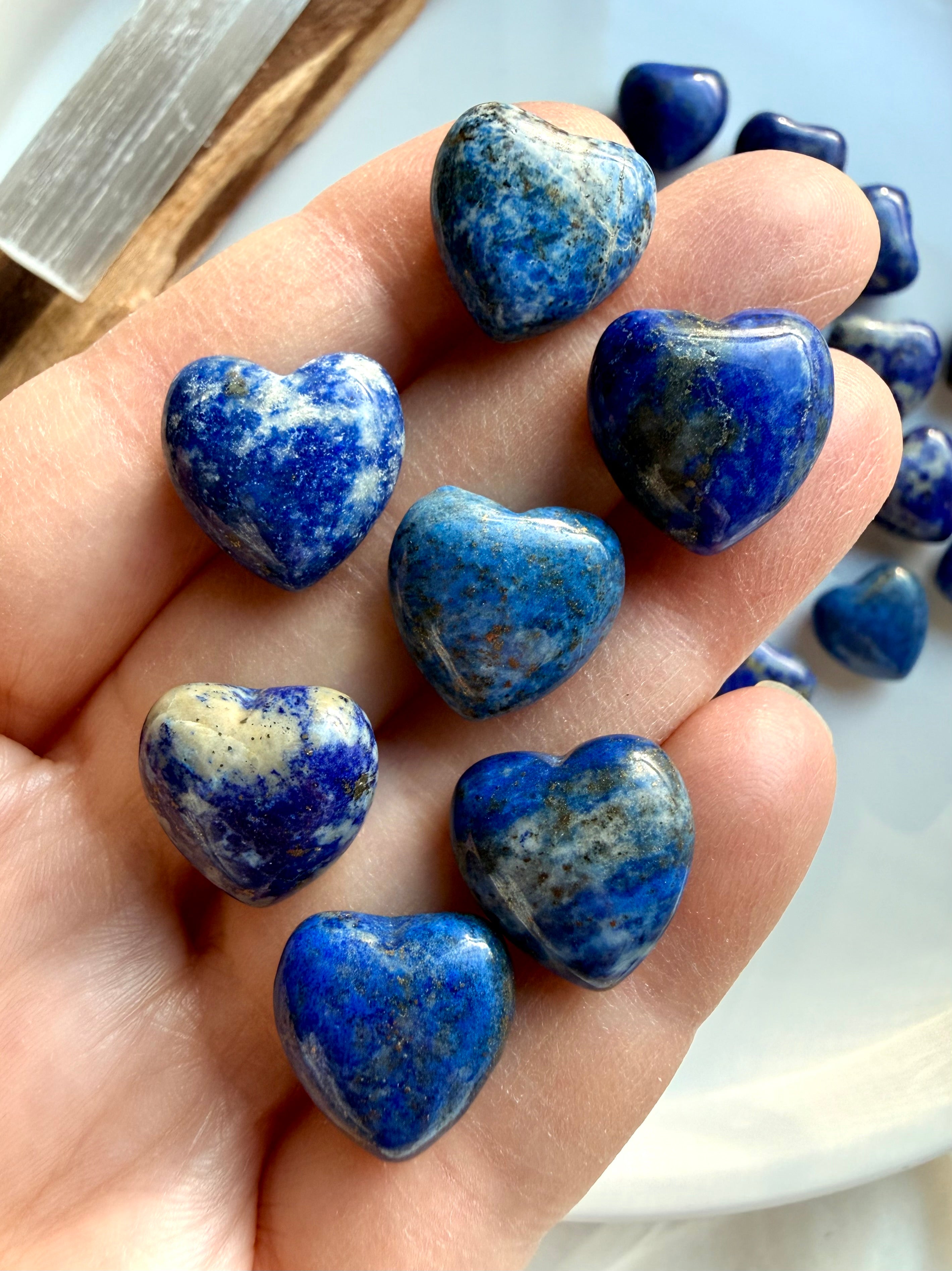Mini Lapis Lazuli heart crystals resting in hand, polished blue stone hearts with natural calcite patterns, small pocket-size healing crystals