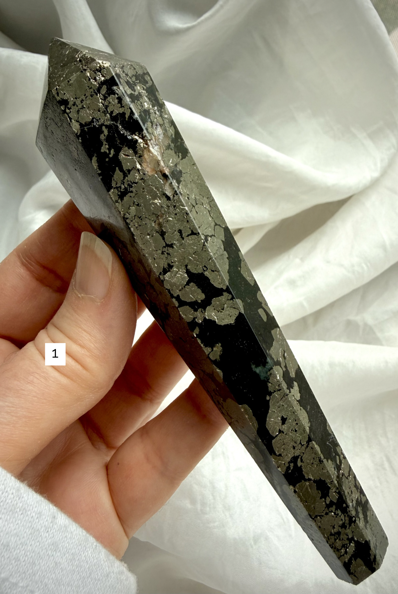 pyrite wand in black matrix held in hand polished crystal point option 1