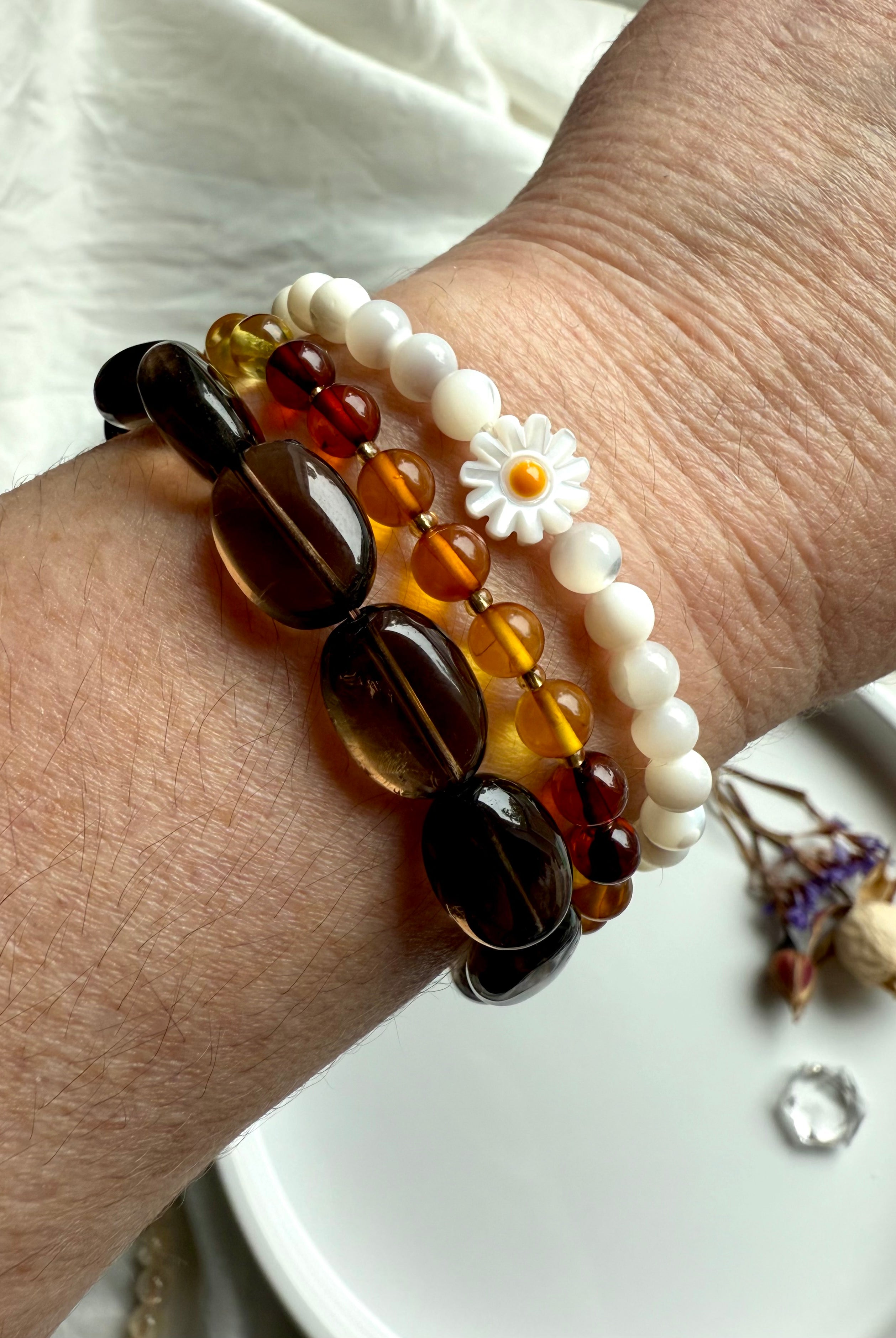 Smoky Quartz bracelet stacked with amber and mother of pearl daisy bracelets – earthy crystal jewelry for grounding, balance, and boho style