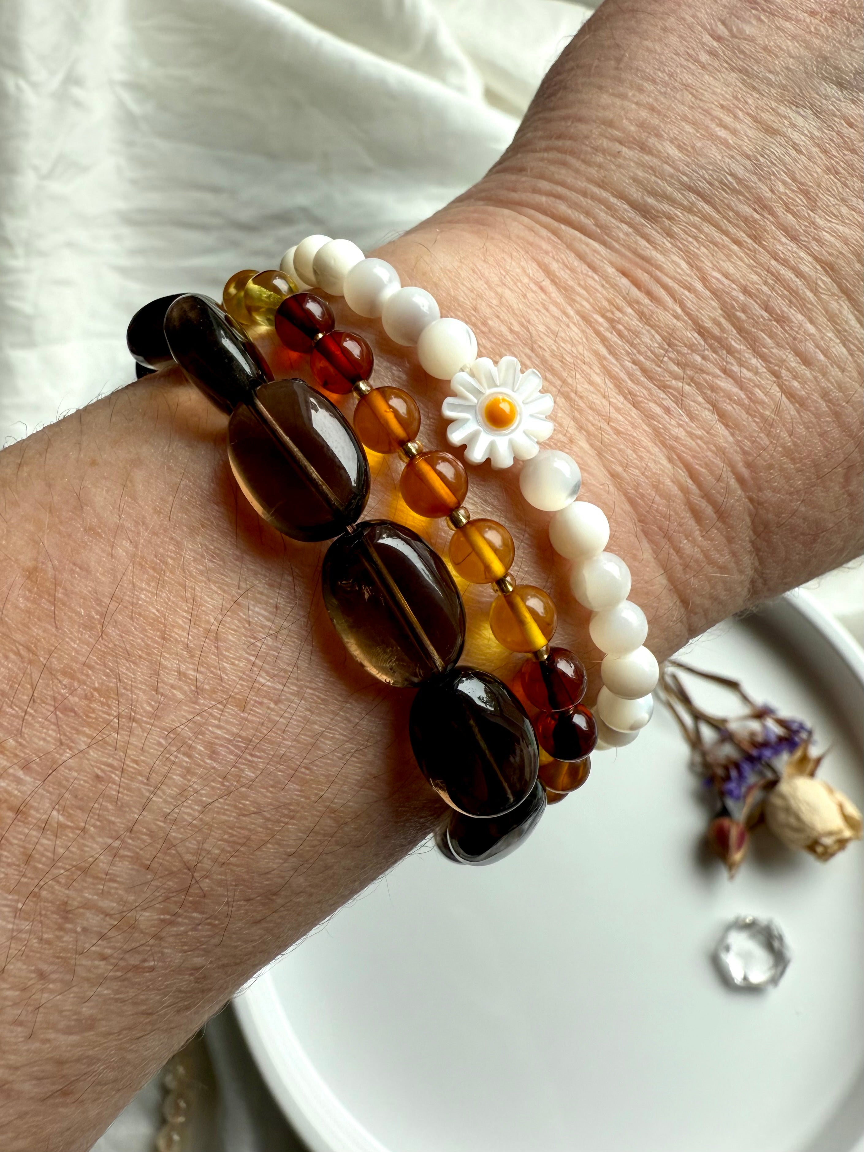Smoky Quartz bracelet stacked with amber and mother of pearl daisy bracelets – earthy crystal jewelry for grounding, balance, and boho style