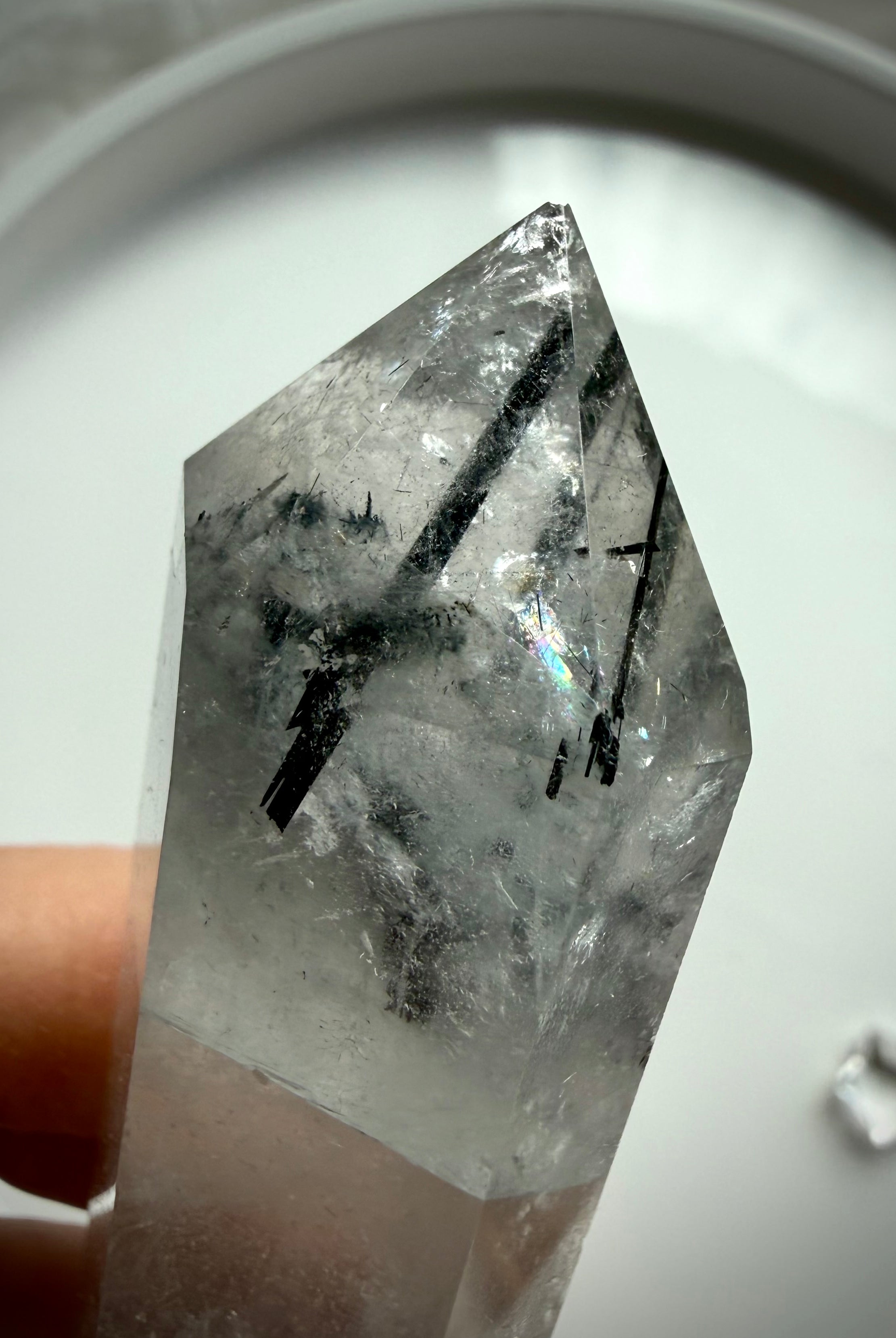 tourmalinated quartz crystal point with visible rainbow and dramatic black rutile inclusions