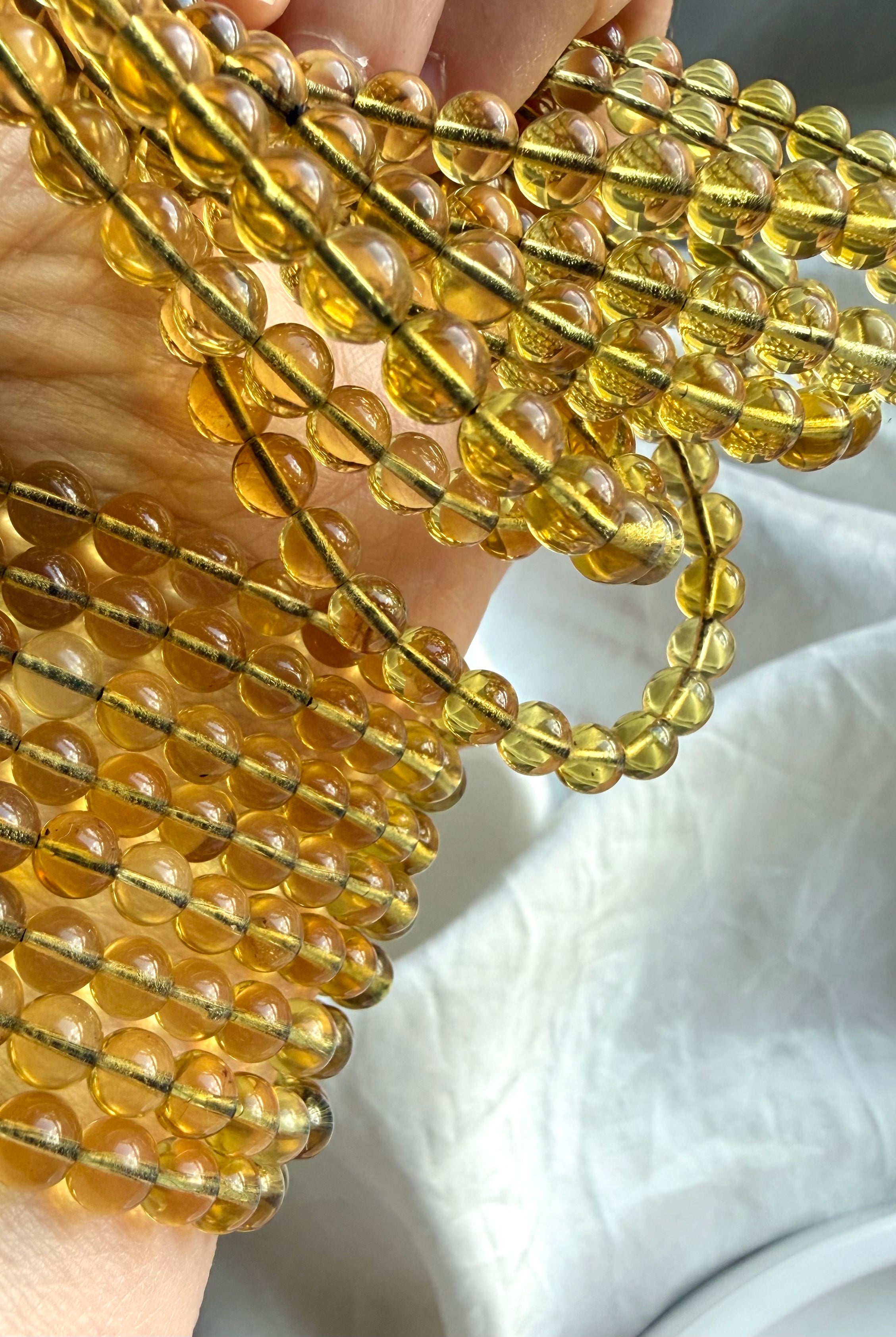 Blue Amber bracelet stack – Indonesian UV reactive amber bead bracelets glowing golden in natural light