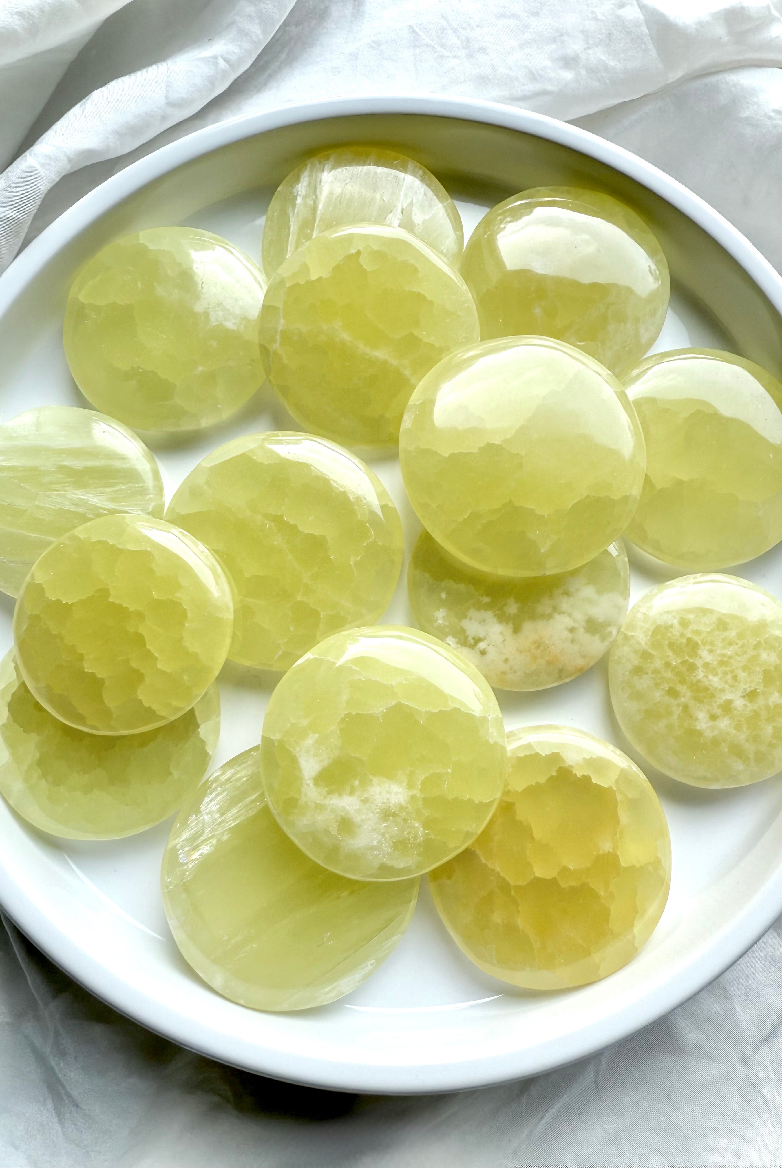 Lemon Calcite meditation stones in a white dish – polished yellow crystal discs for clarity, confidence, and solar plexus chakra healing