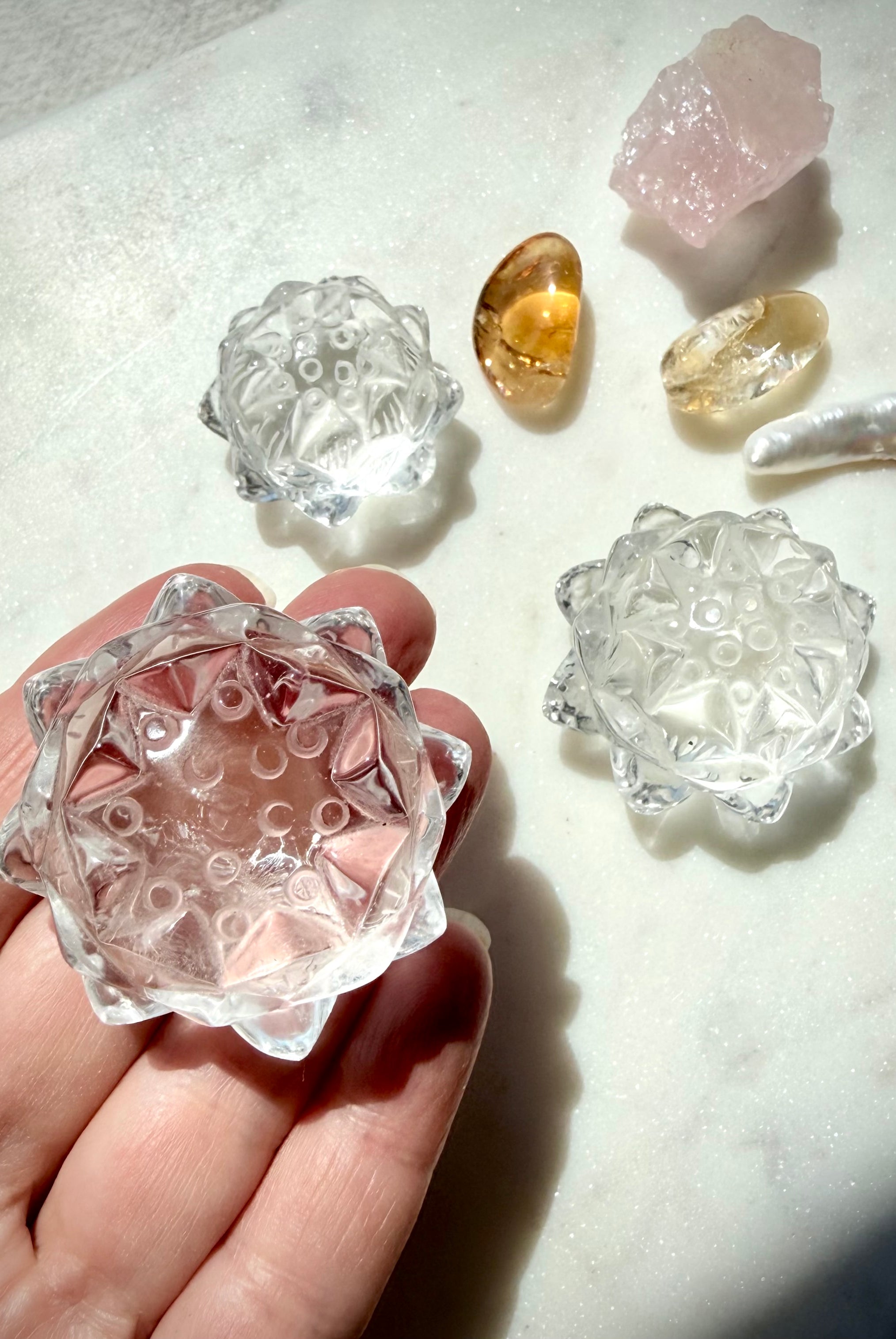 Clear Quartz lotus flower carving held with Citrine and other crystal lotuses showing natural variation and clarity