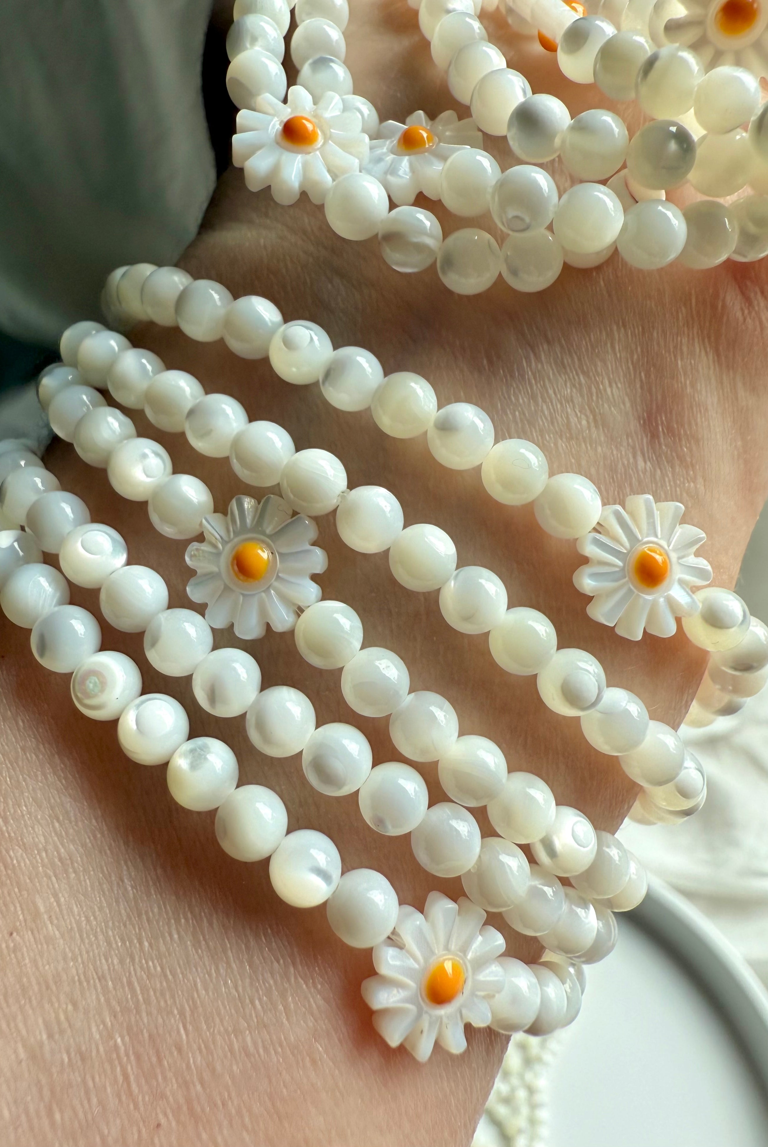 Mother of Pearl daisy bracelets stacked on wrist – opalescent shell bead jewelry for lighthearted boho style
