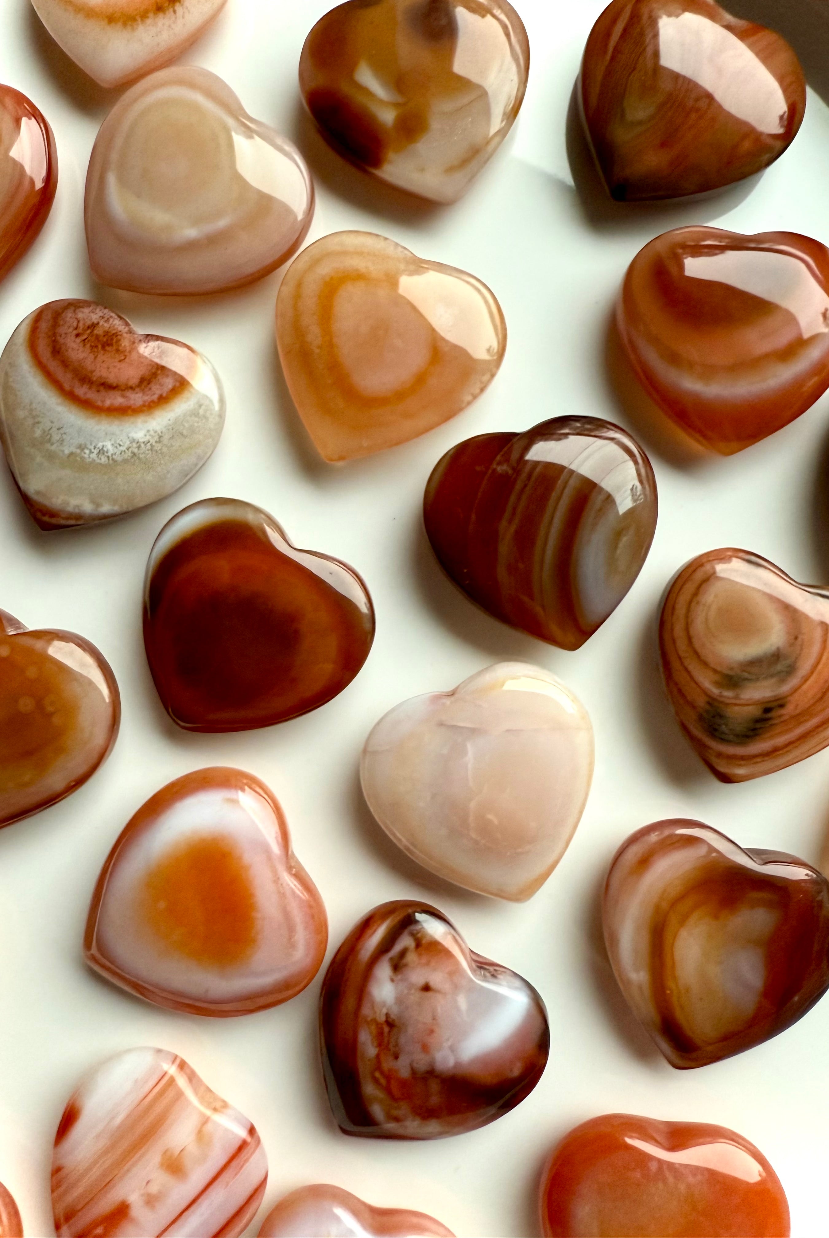 Polished mini Carnelian hearts highlighting natural agate banding, warm orange sacral chakra crystal for emotional balance and joy