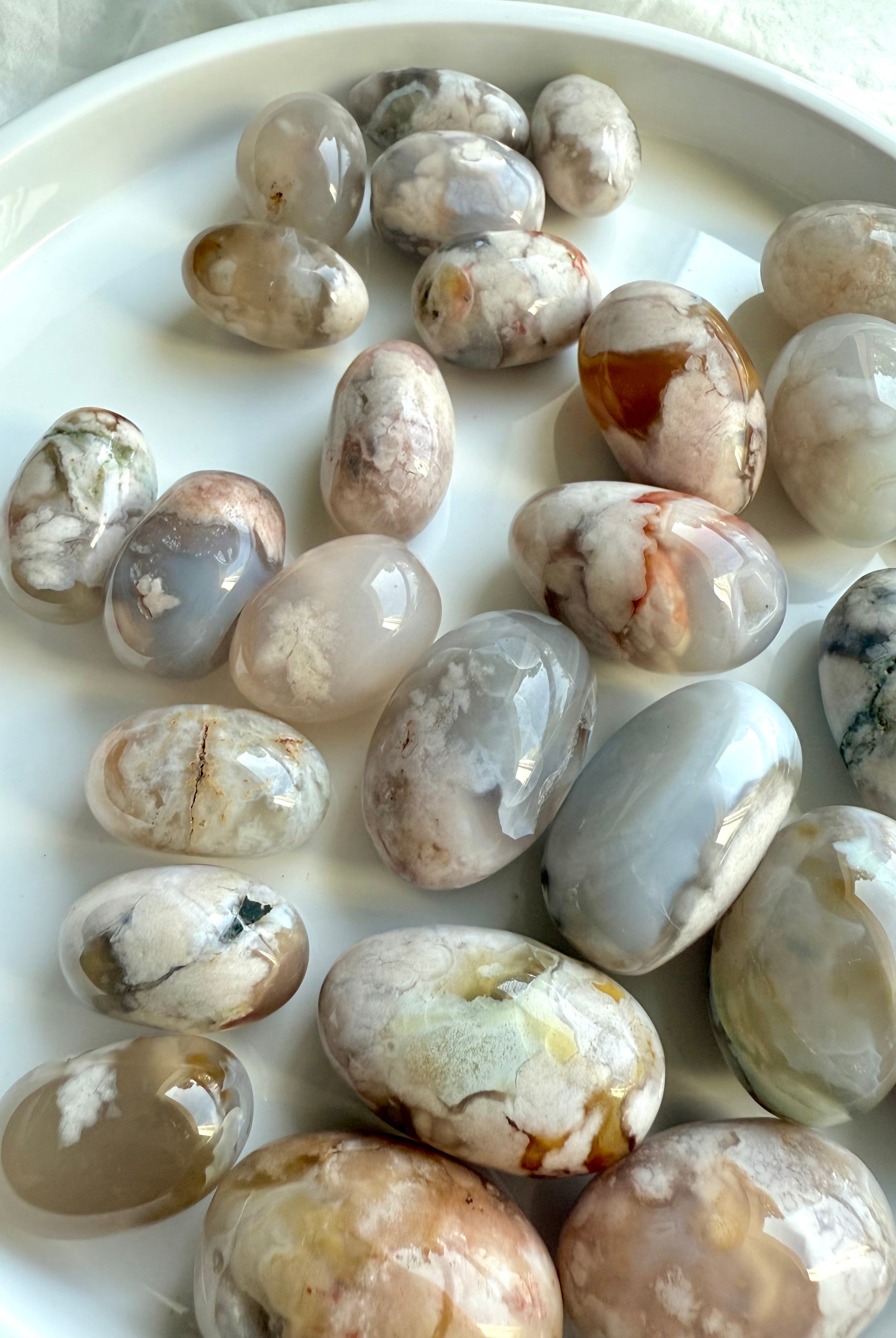 High quality Flower Agate tumbled stones with beautiful pastel colors on a white plate