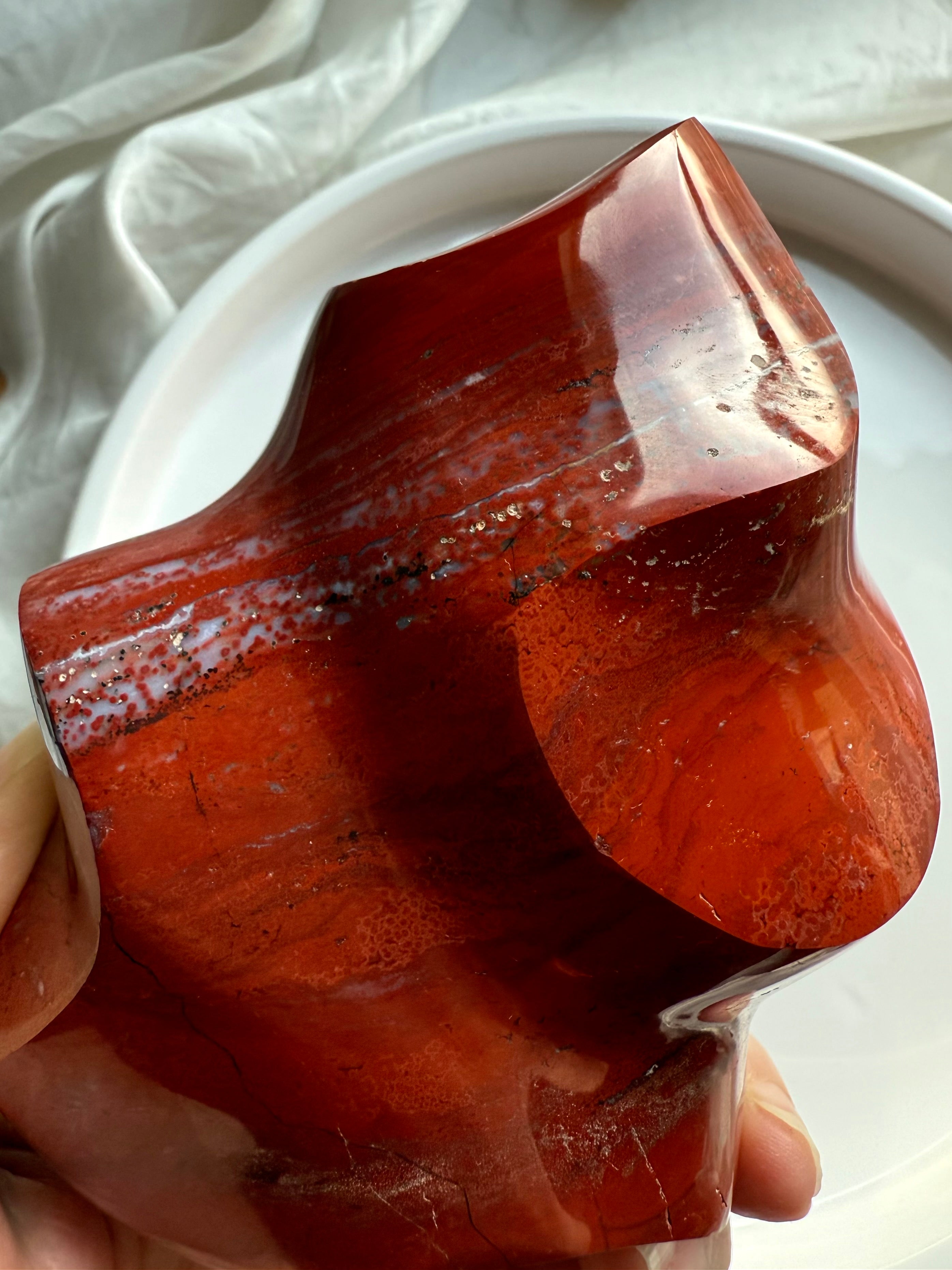 Closeup angle of Red Ocean Jasper flame showing smooth carved curves, grounding red tones, and natural veining.
