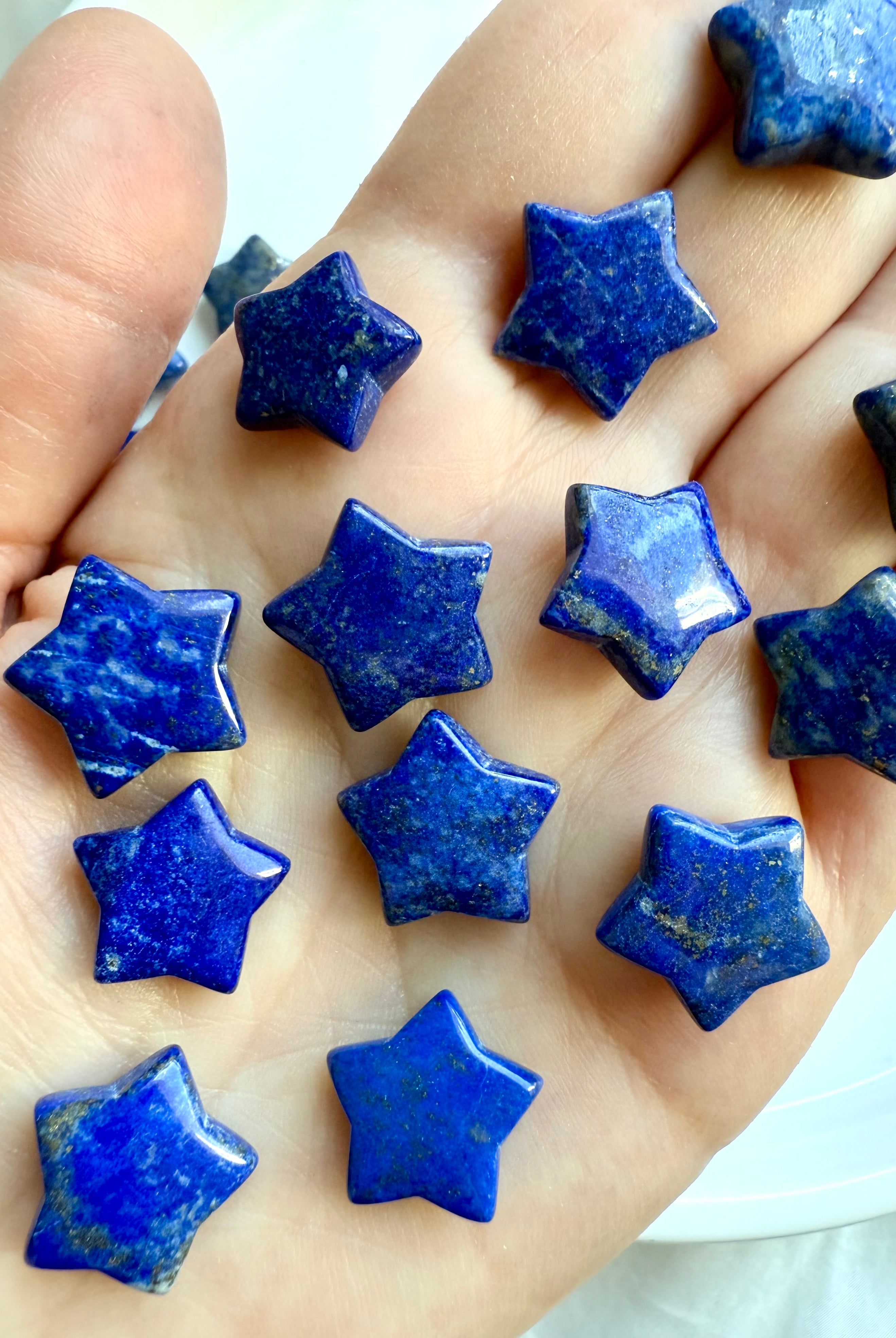 Close-up of Lapis Lazuli star crystal with deep blue color and metallic flecks on a woman's hand
