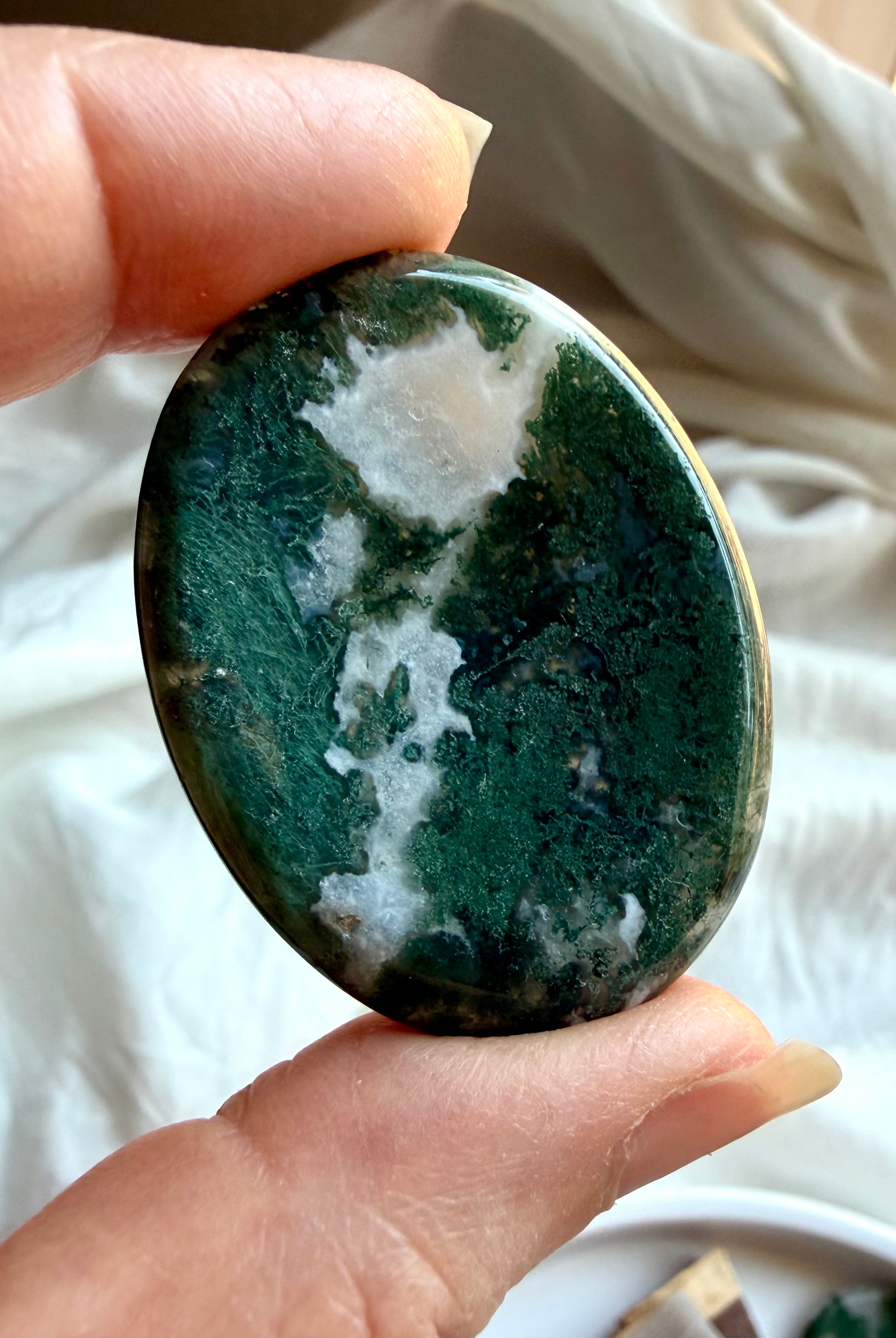 Moss Agate oval worry stone held in hand with translucent quartz, forest green inclusions and landscape patterns