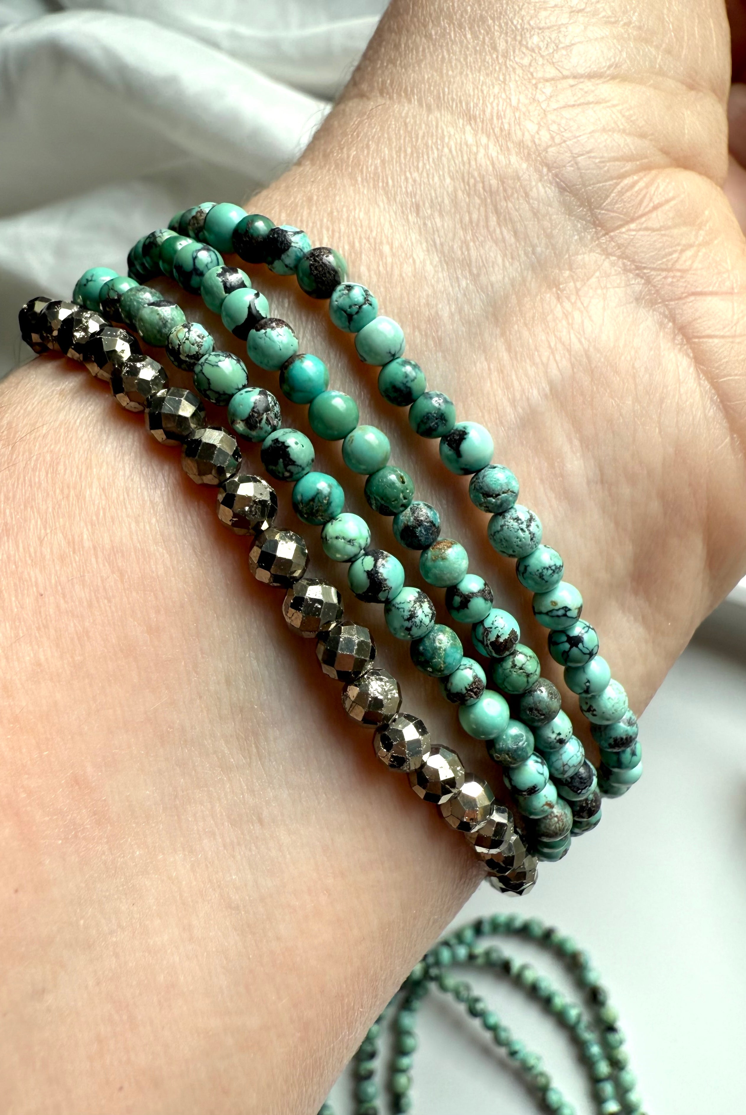 Layered wrist stack featuring turquoise and faceted pyrite bracelets for grounding + protection