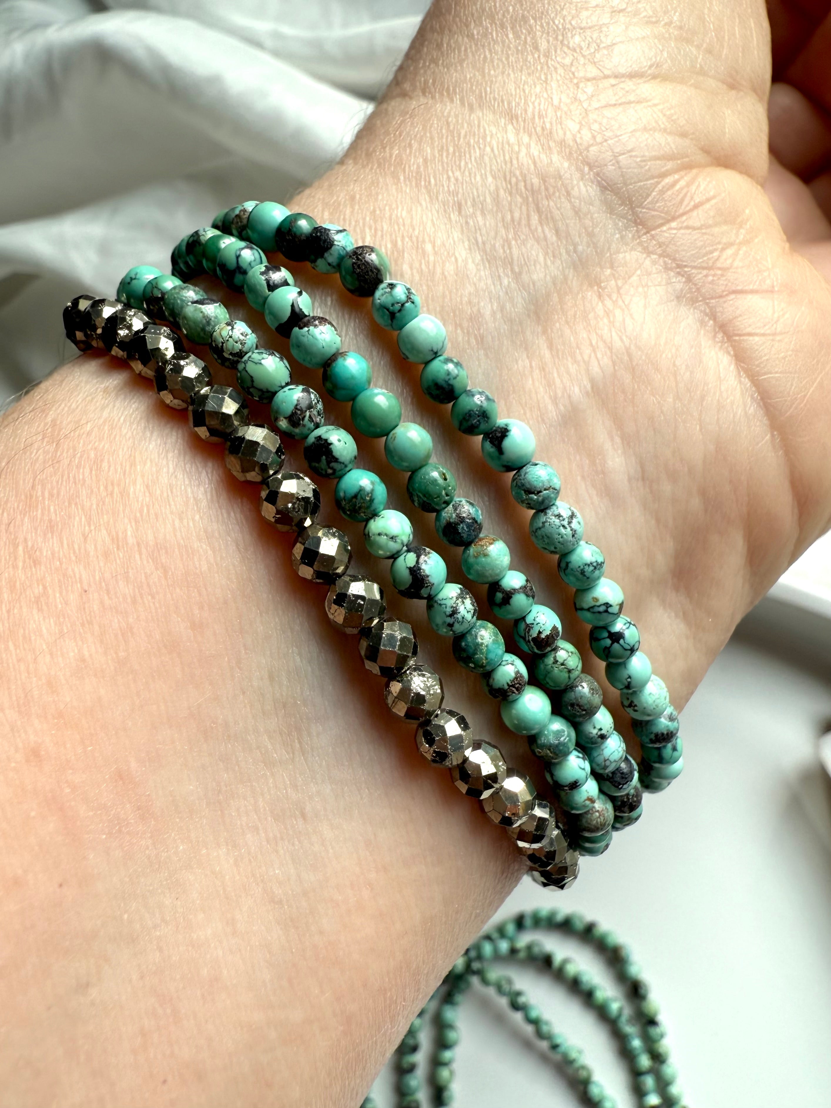 Layered wrist stack featuring turquoise and faceted pyrite bracelets for grounding + protection