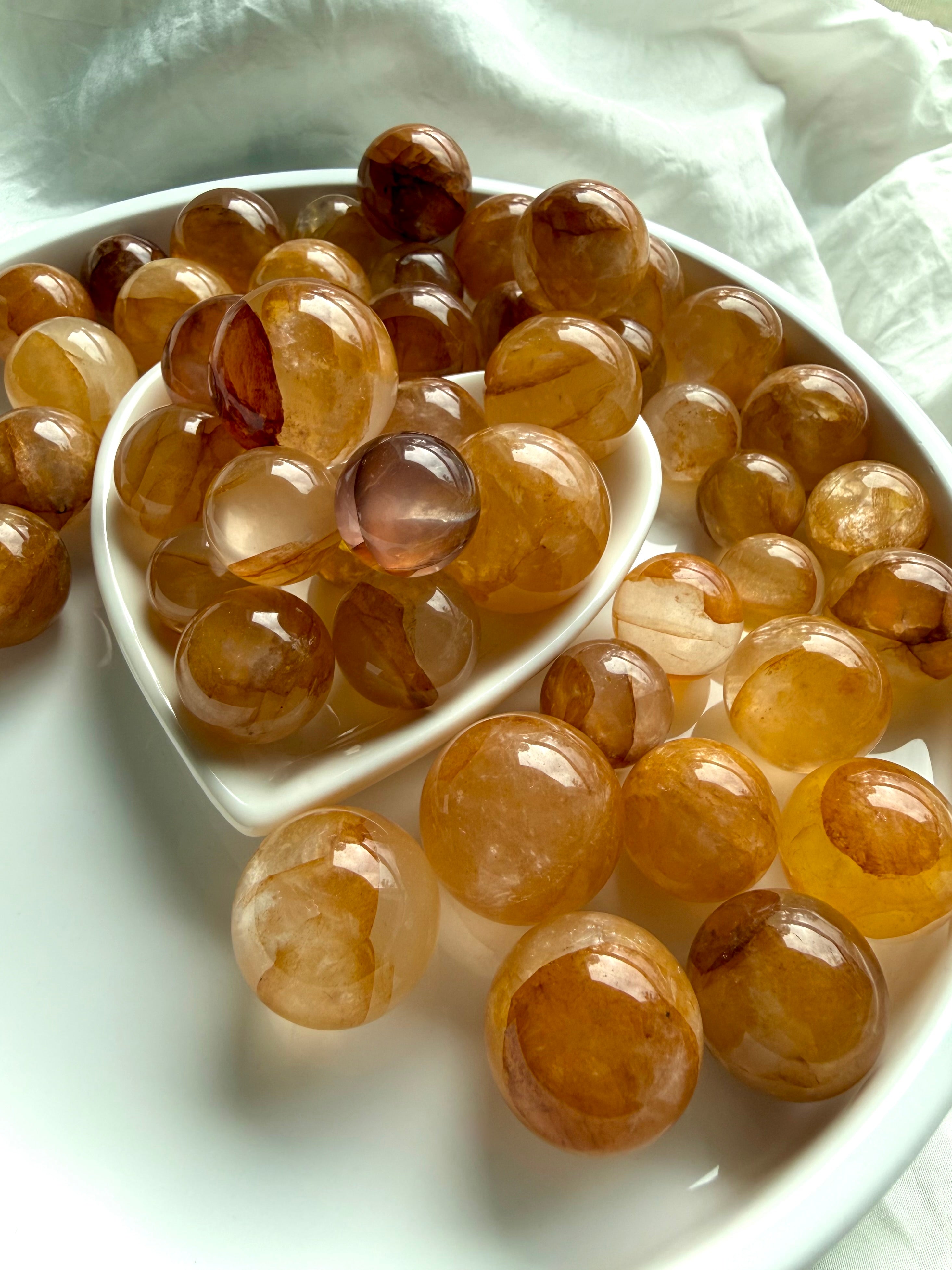 golden healer quartz mini spheres in a heart bowl showing range of golden tones and natural internal patterns