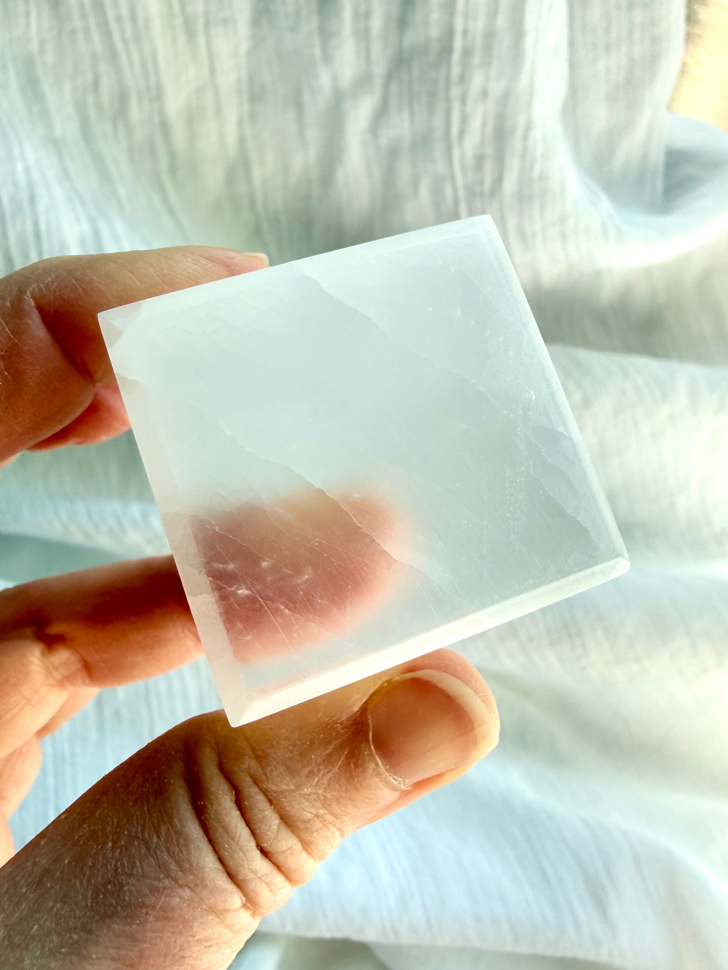 Polished Selenite cube glowing in sunlight with translucent edges and natural satin spar banding