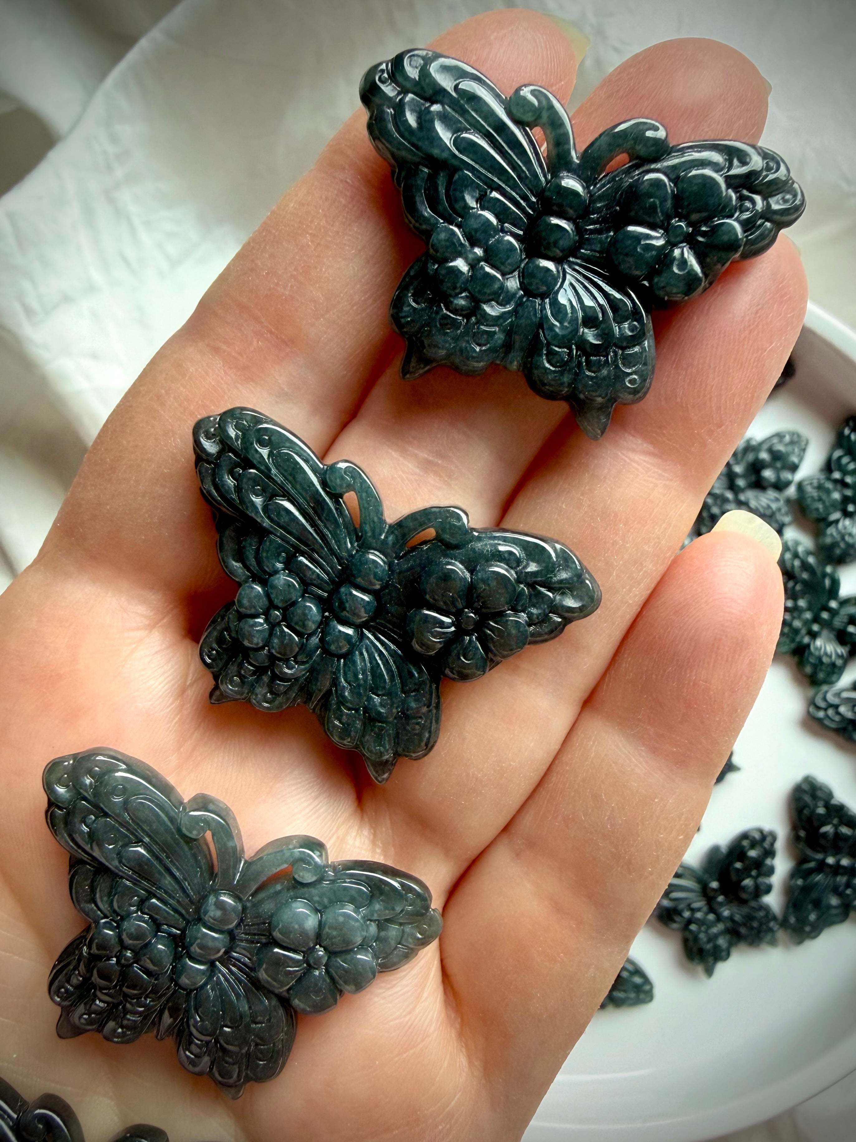 Hand holding Wuji jade crystal butterfly carvings made from natural Guatemalan jade