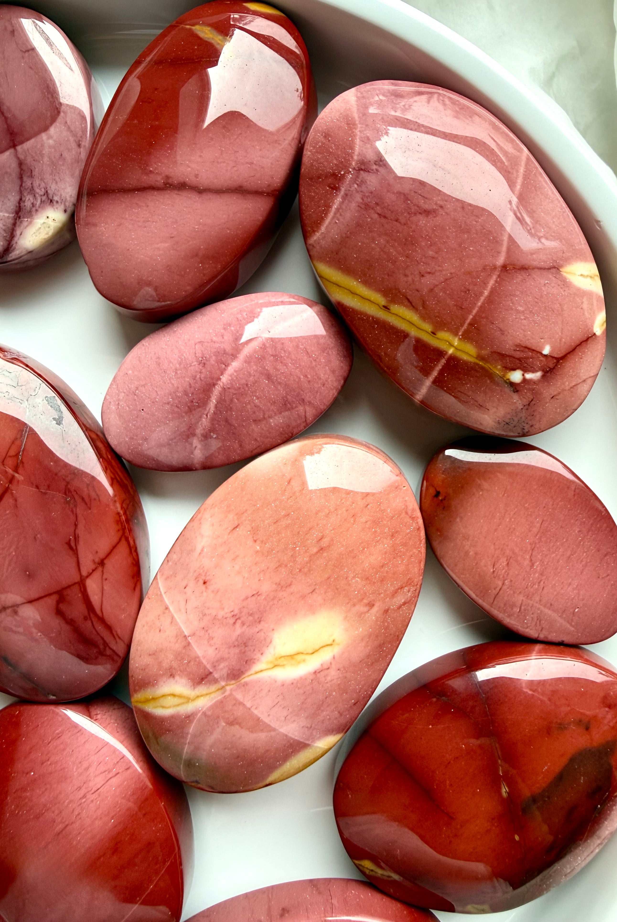 assorted Mookaite Jasper palm stones with warm earthy patterns and polished finish for stability and personal strength