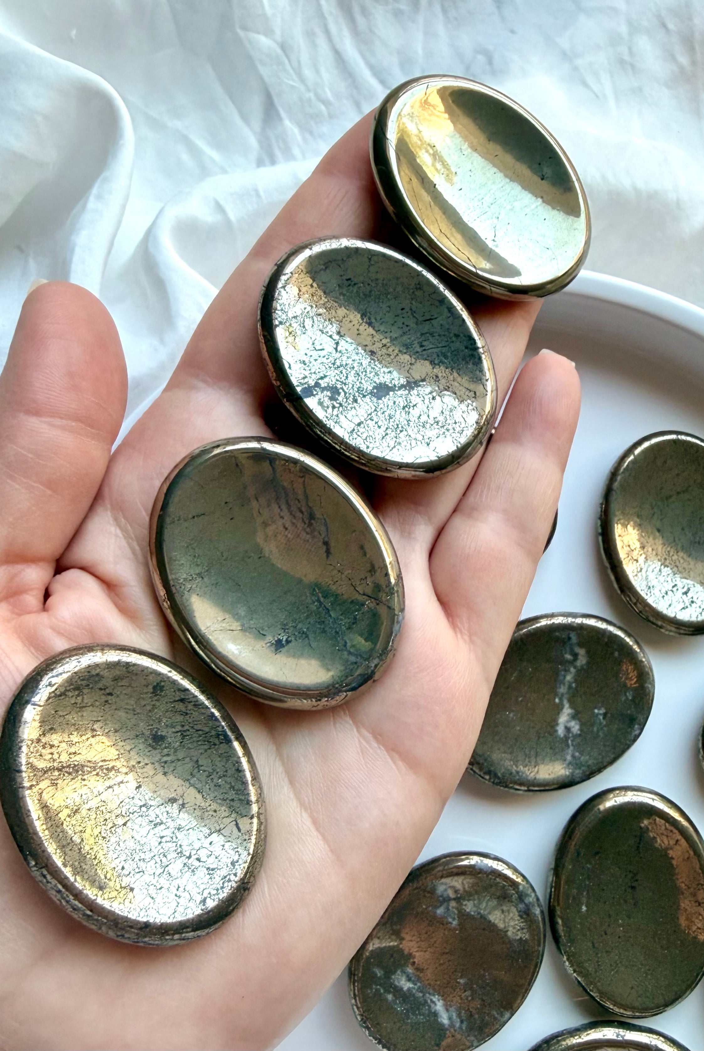 Polished Pyrite worry stones shown on hand highlighting metallic gold sheen and natural variation