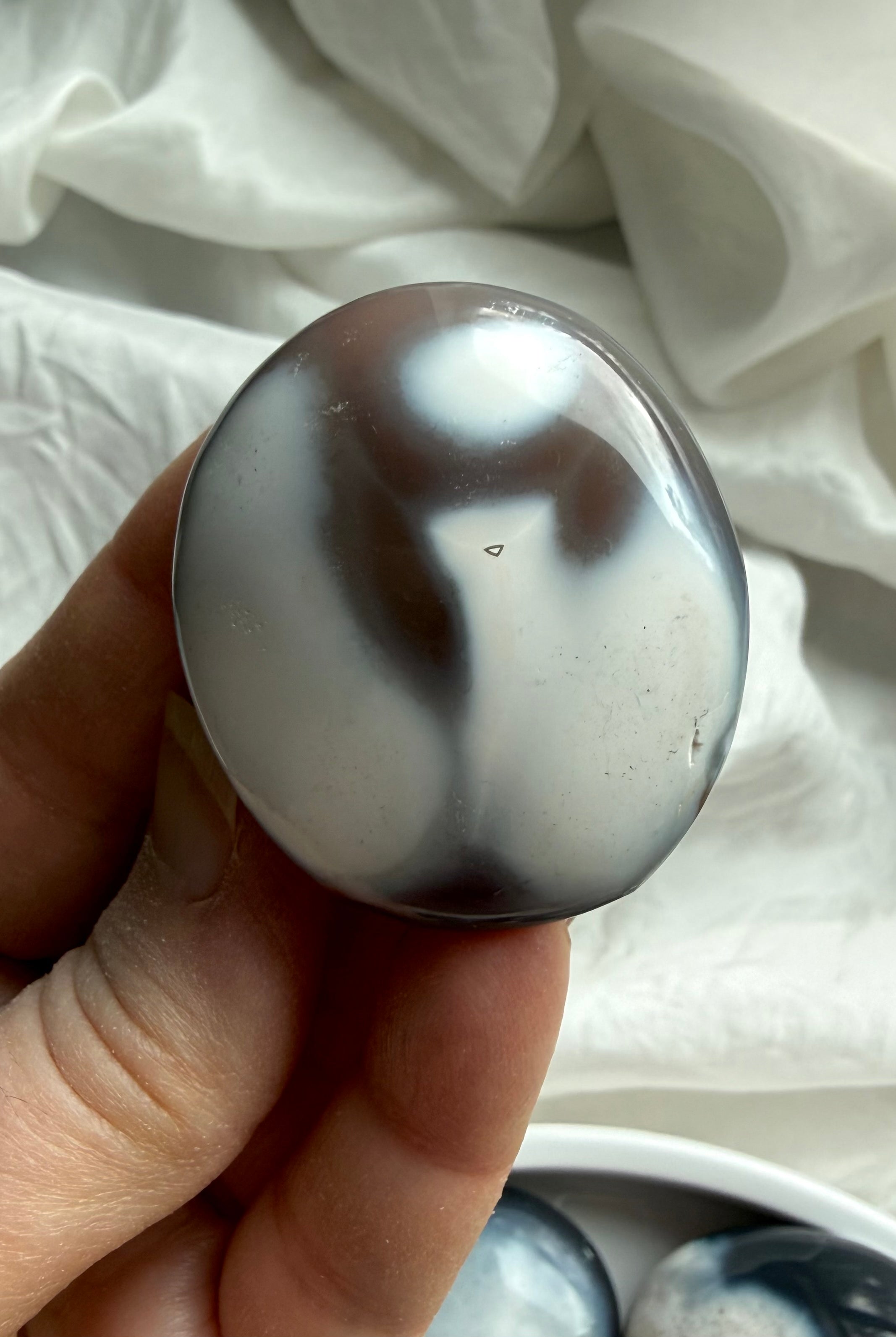 Orca Agate palm stone with black and white patterns, a calming crystal for forgiveness, emotional grounding, and inner peace