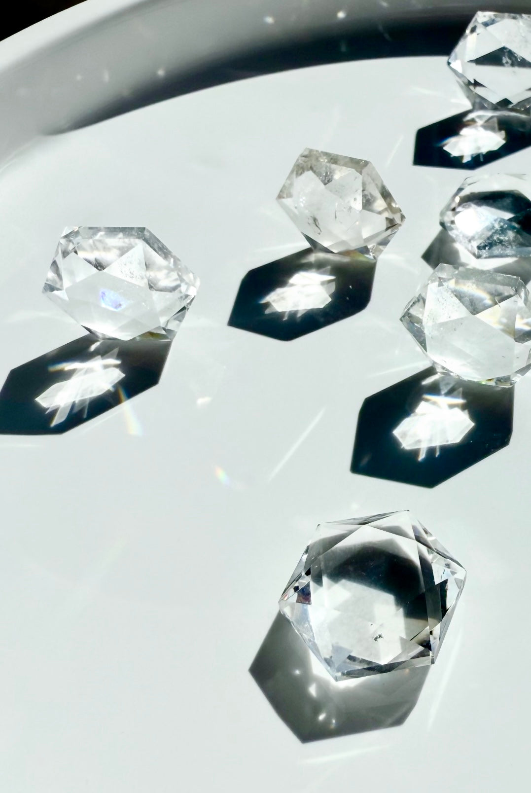 Angled view of multiple Clear Quartz hexagons standing on edges, casting radiant hexagonal light and shadows