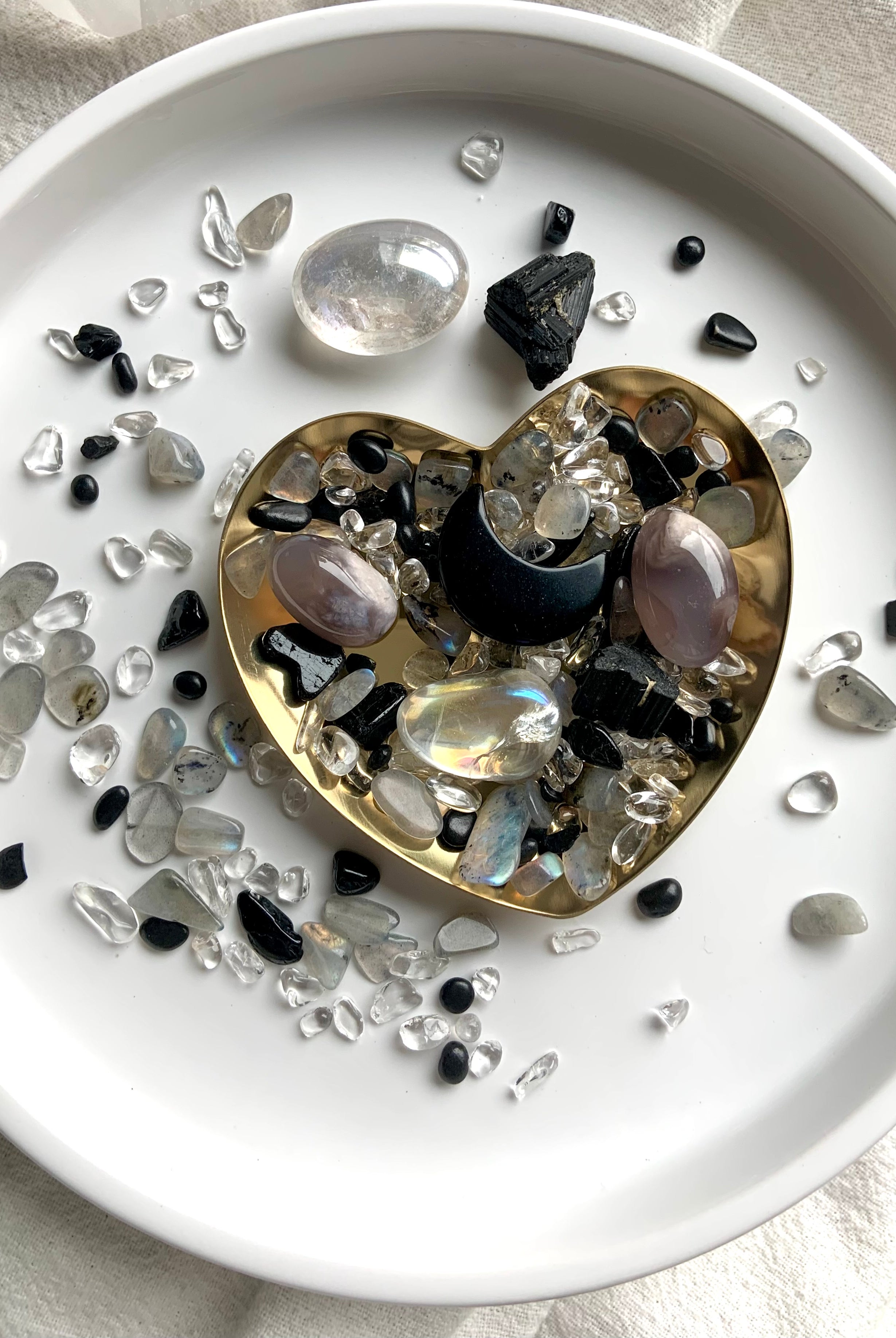 Moon Phase Crystal Confetti blend just a little witchy with a Black Obsidian Crescent Moon Carving. Pic shows the "confetti + tumbles + moon + bowl" option spread out on a white plate