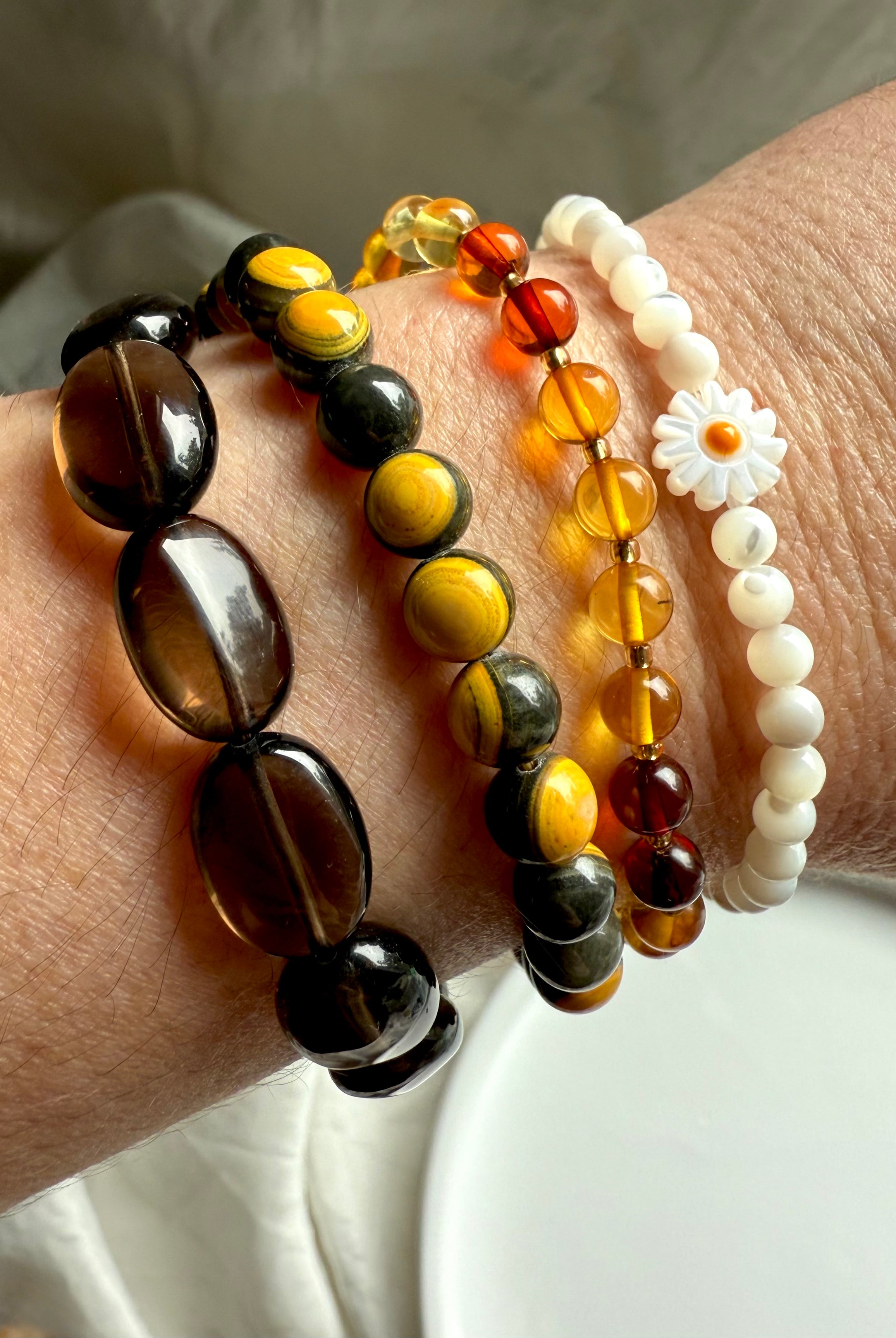 bumblebee jasper bracelet stacked with smoky quartz and mother of pearl daisy bracelets, crystal arm candy for solar plexus healing, grounding, and joy