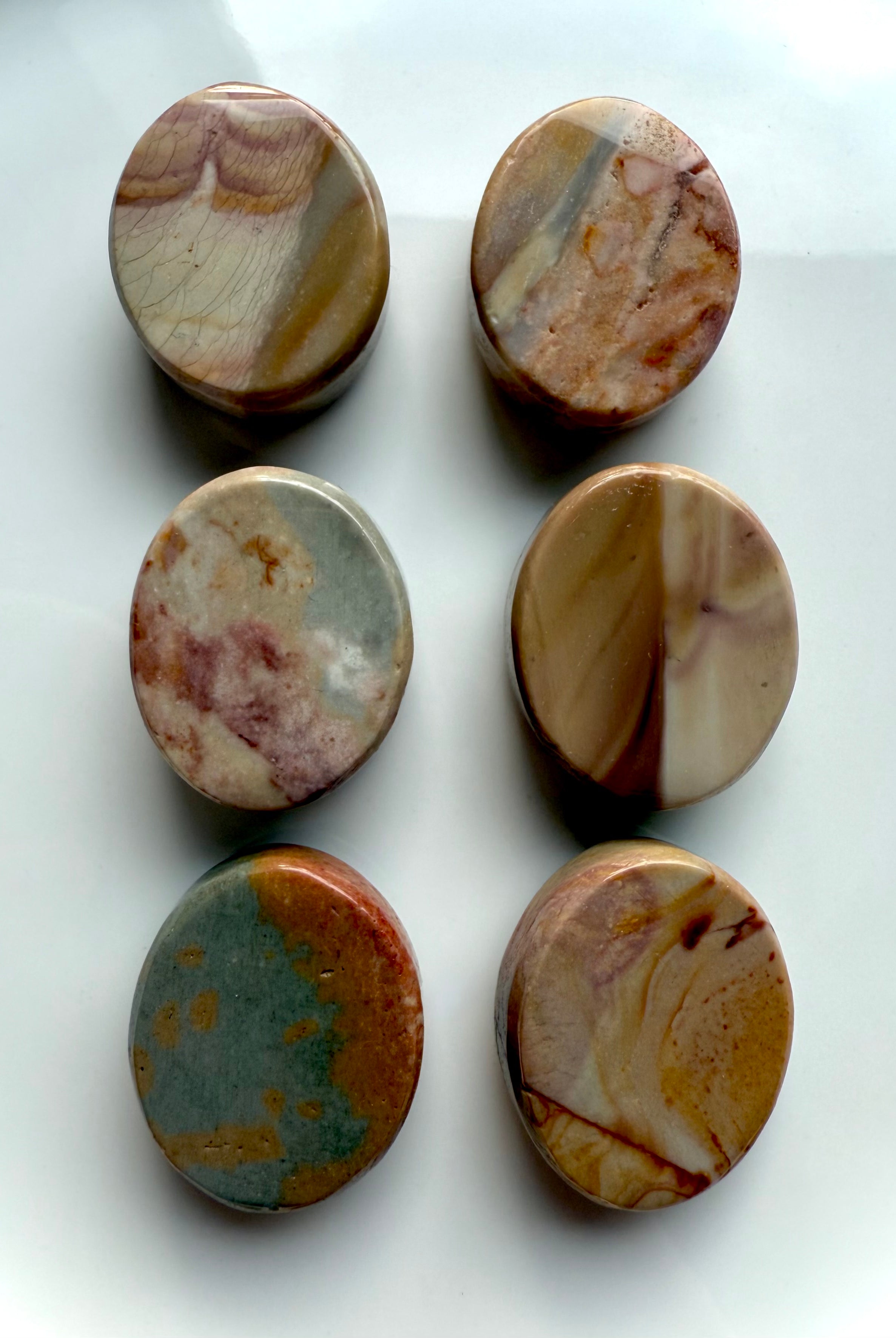 Assorted Polychrome Jasper cabochons shown from the back to highlight organic markings and desert-tone patterns — earthy crystals for balance and stability.