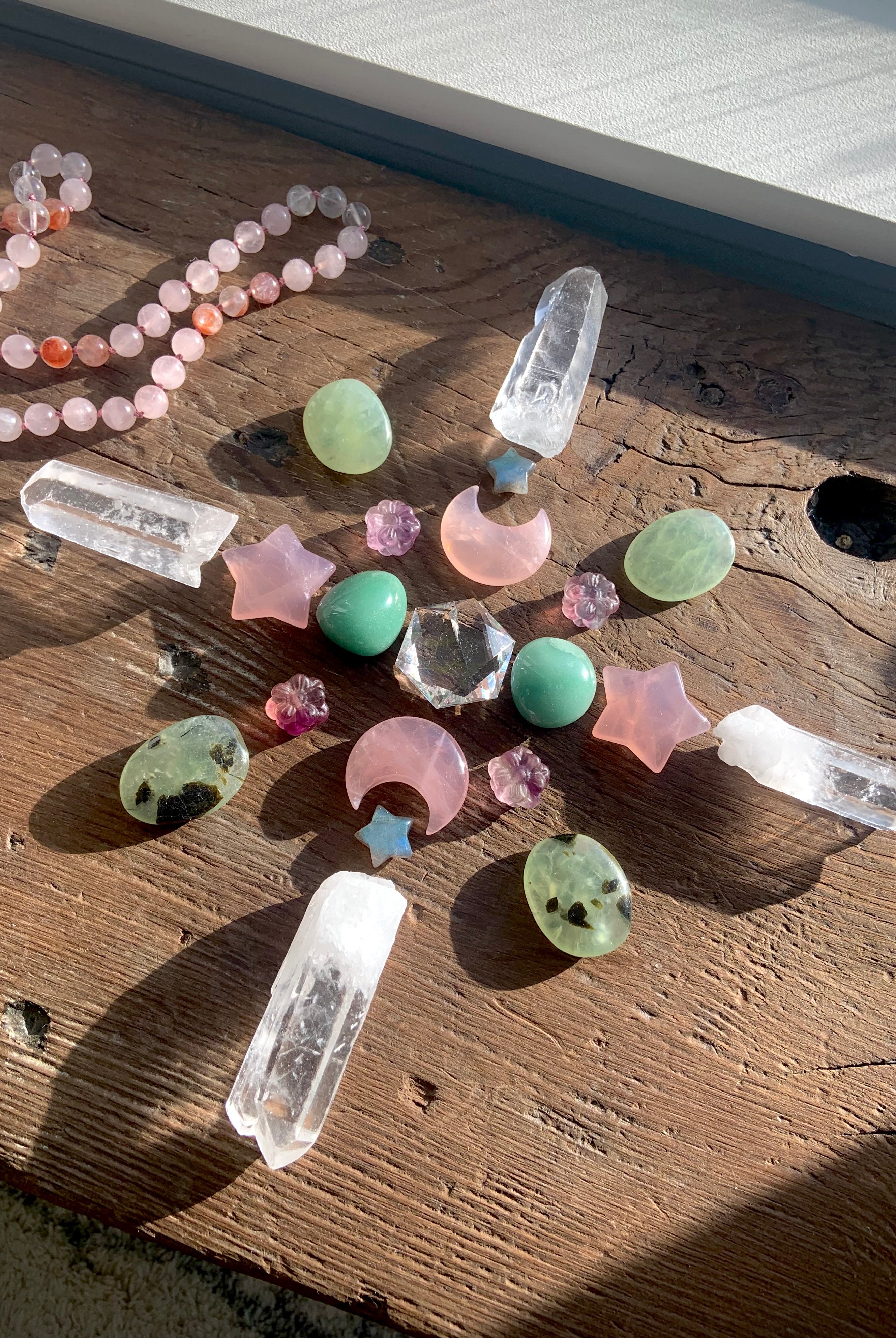 Crystal grid with large Clear Quartz hexagon centerpiece, surrounded by rose quartz moons and stars, prehnite tumbles, labradorite stars, fluorite flowers, and lemurian quartz points
