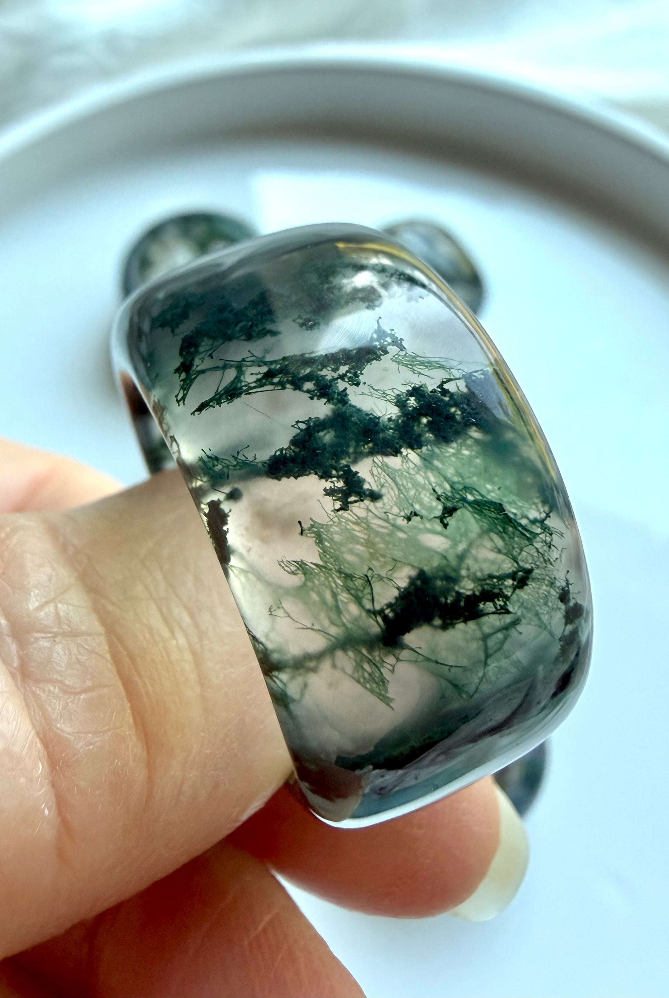 close-up moss agate statement ring worn on finger with scenic dendritic inclusions and polished translucent finish