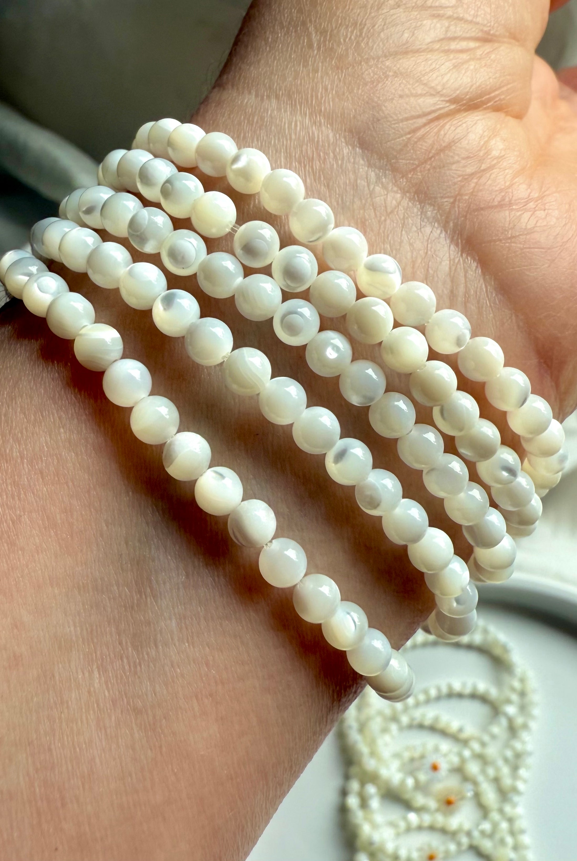 Side view of Mother of Pearl bracelets on wrist, showing glossy round shell beads with natural iridescence