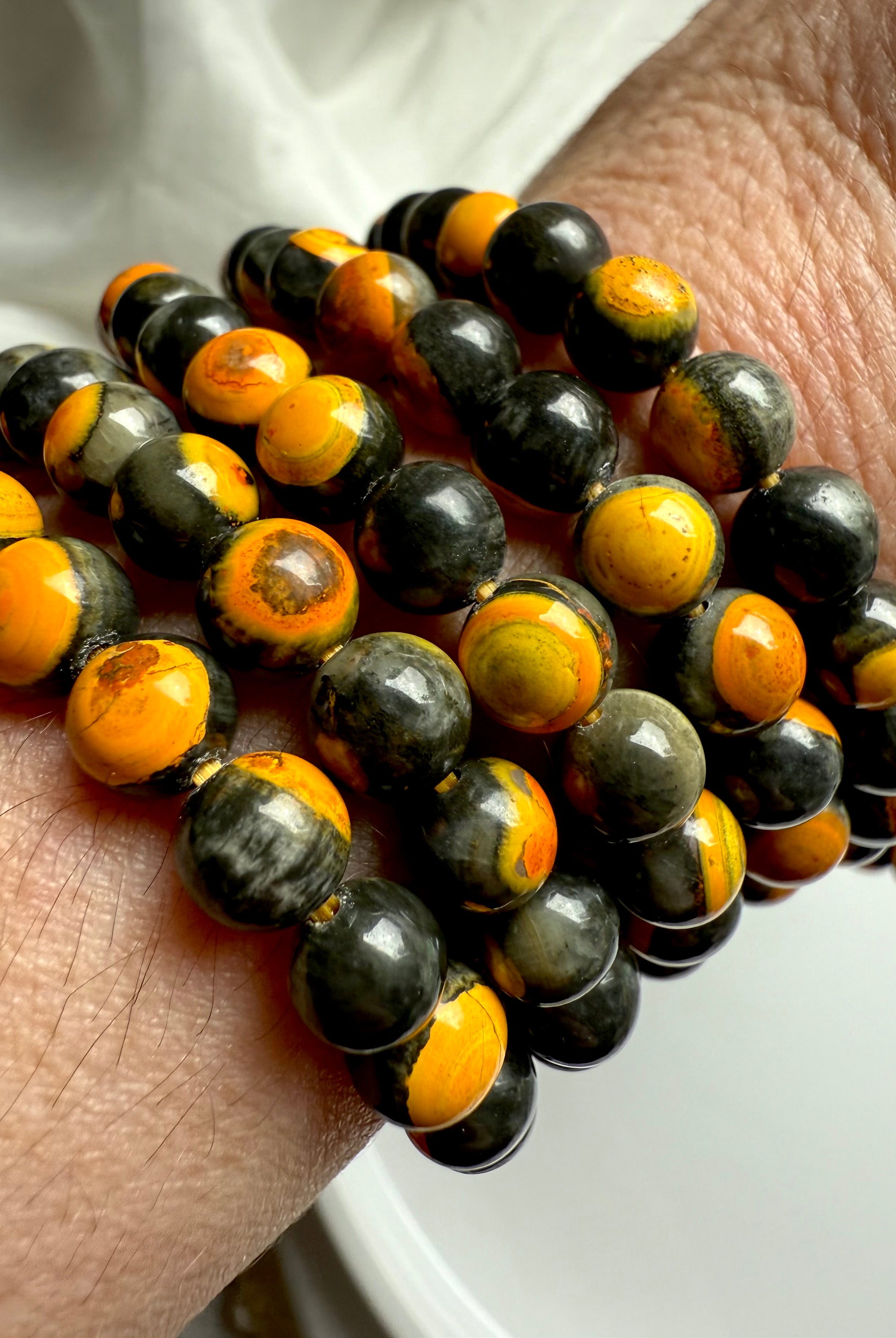 Close-up of bumblebee jasper beads showcasing swirls of yellow, charcoal, and orange — energizing stone for joy, confidence, and clarity