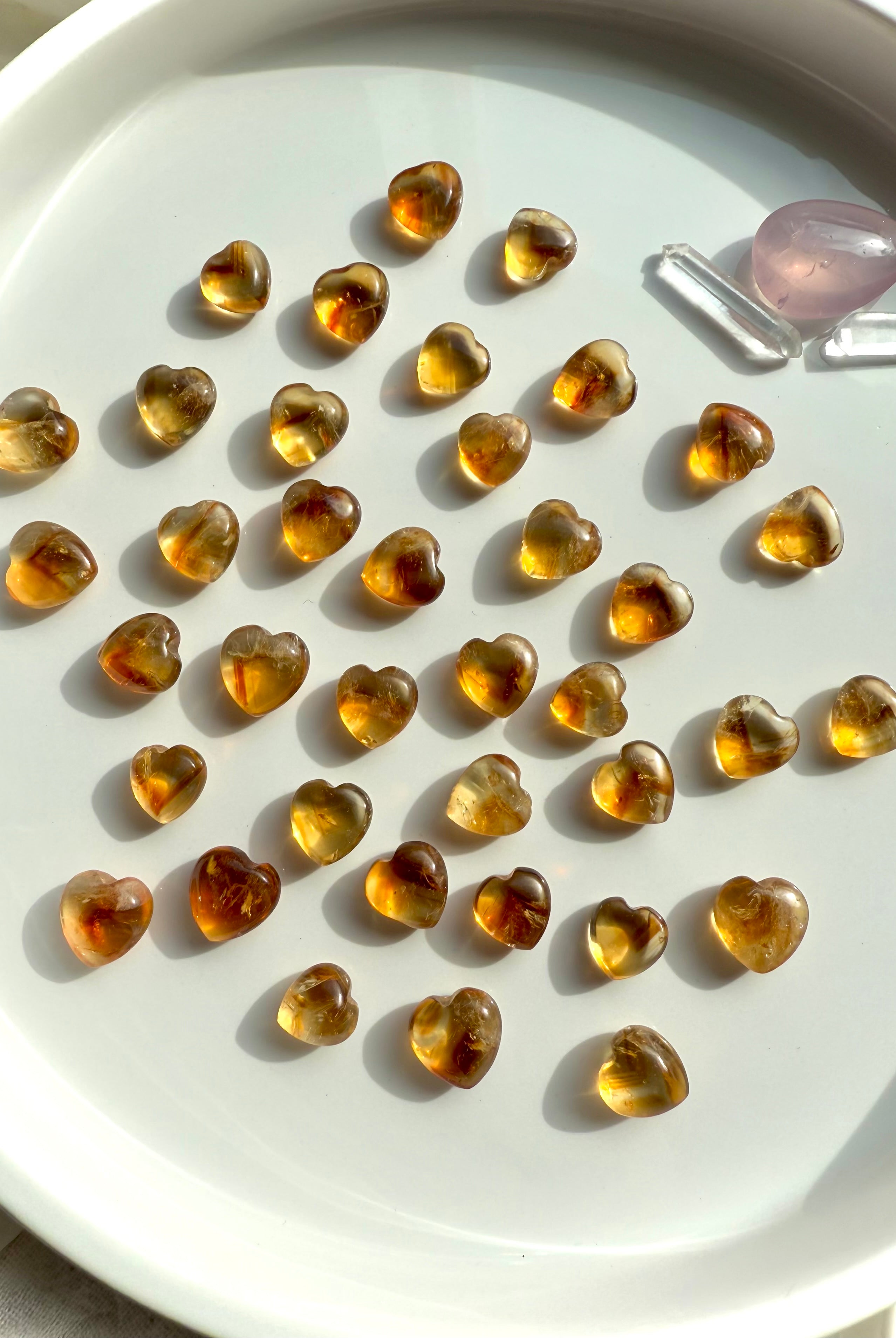 Mini Citrine Crystal Hearts shown on a white plate, photographed in natural light