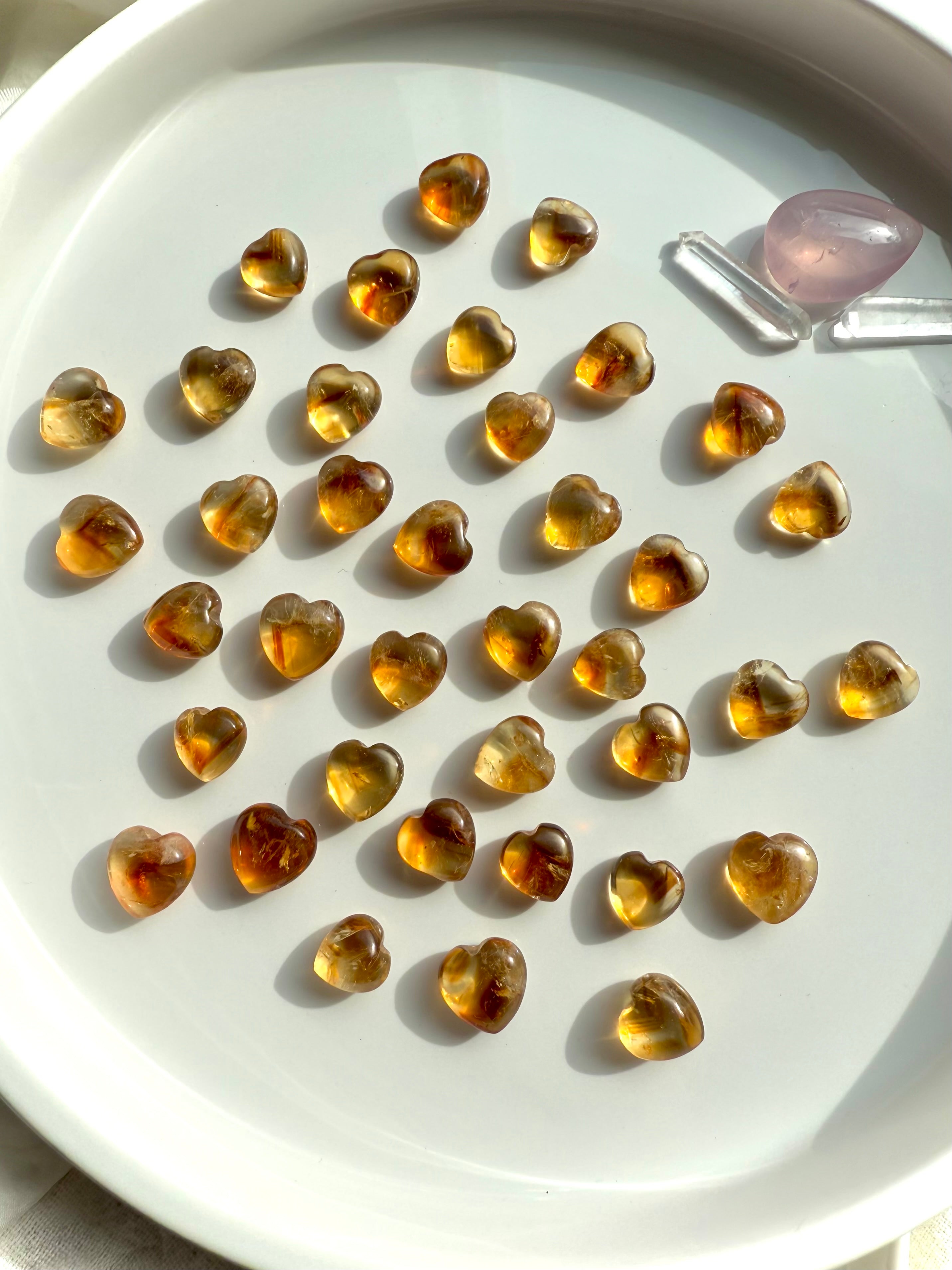 Mini Citrine Crystal Hearts shown on a white plate, photographed in natural light