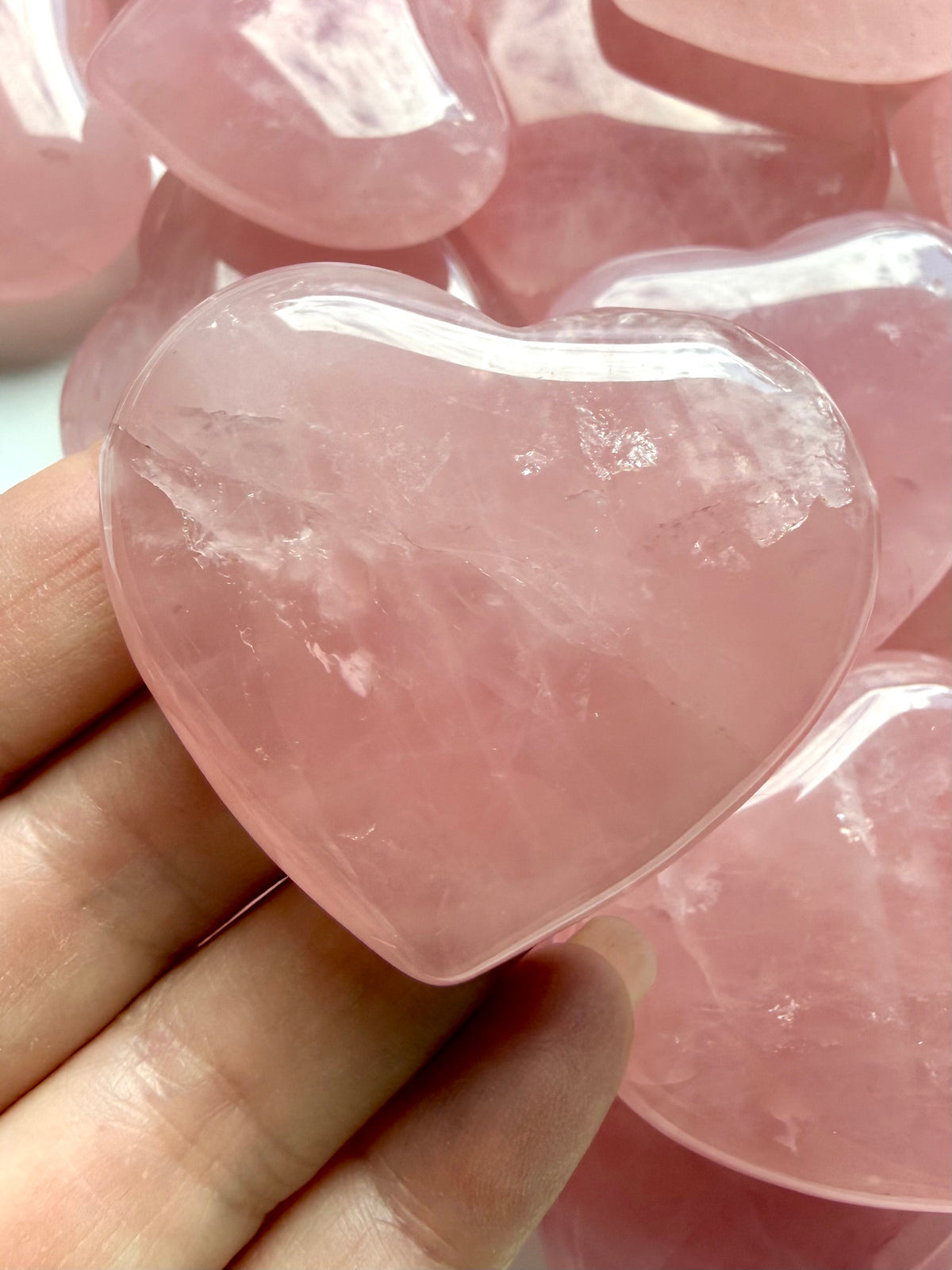Close-up Rose Quartz heart carving showing translucent pink crystal, natural internal patterns and smooth polished surface