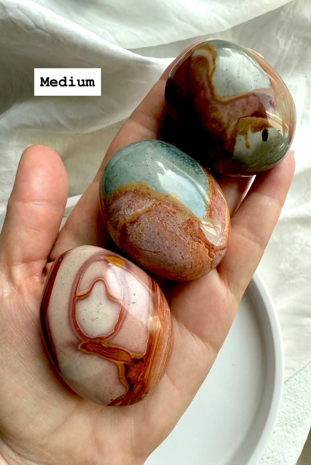 Medium Polychrome Jasper palm stones displayed in hand, showing size, shape, & vibrant earthy colors