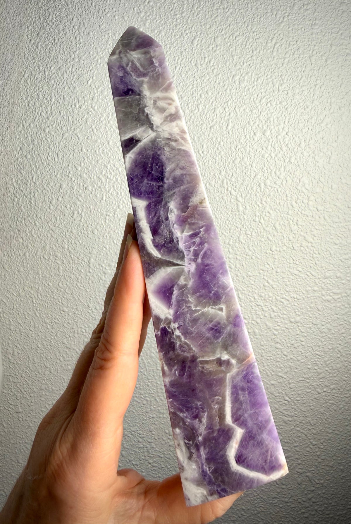 Tall Dream Amethyst crystal point showing its slender shape, rich purple coloring and distinctive zigzag quartz patterns