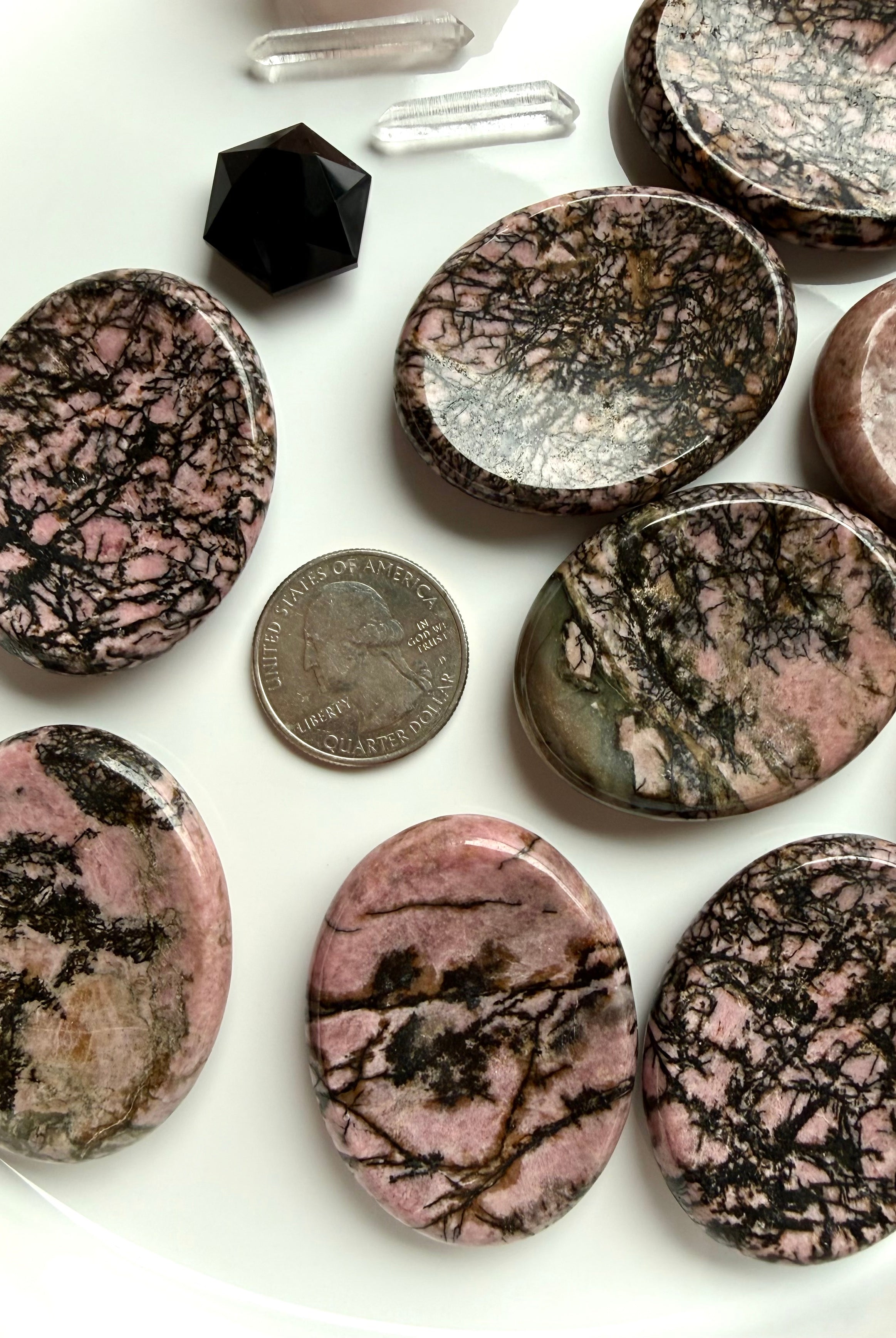 Rhodonite worry stone with US quarter for size comparison on white tray