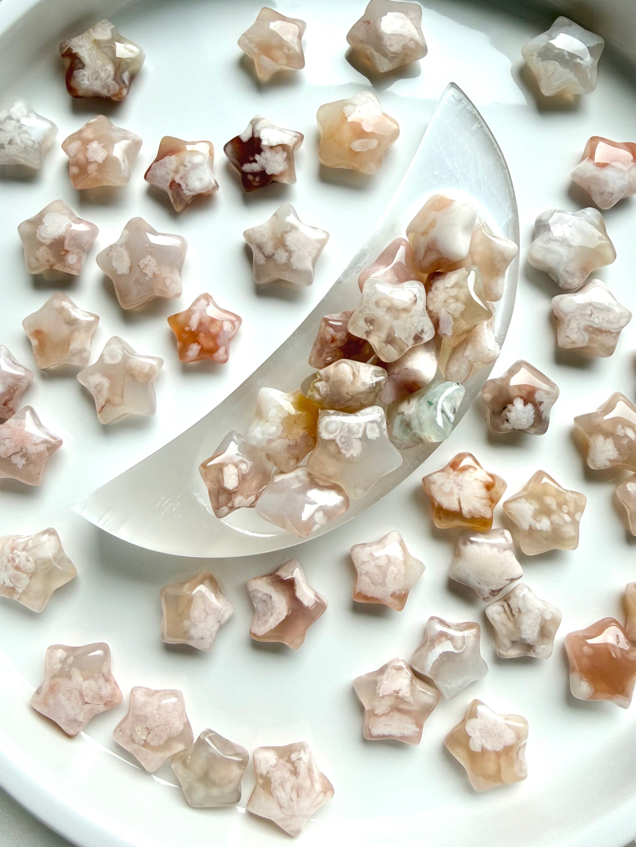 Flower Agate star carvings displayed on a crescent moon bowl with soft pink floral inclusions and celestial altar styling