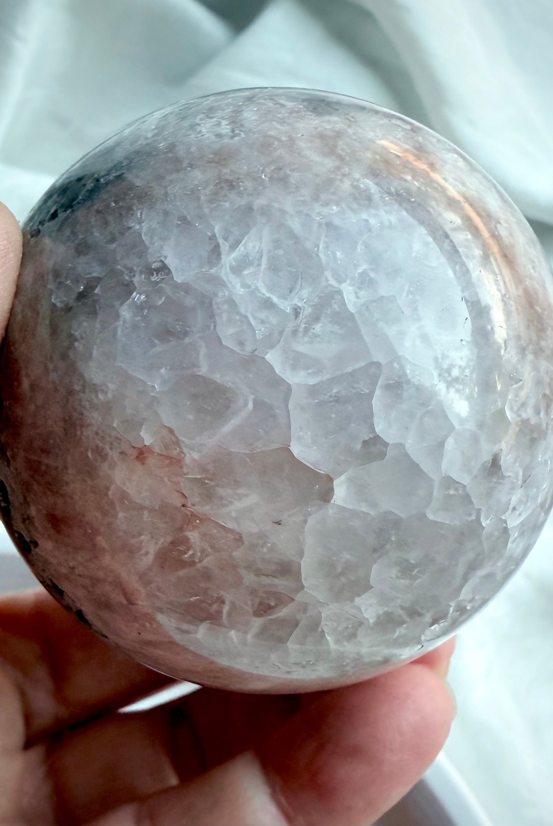 Close-up of agate sphere showcasing polished quartz crystal texture with soft gray and smoky tones, natural light