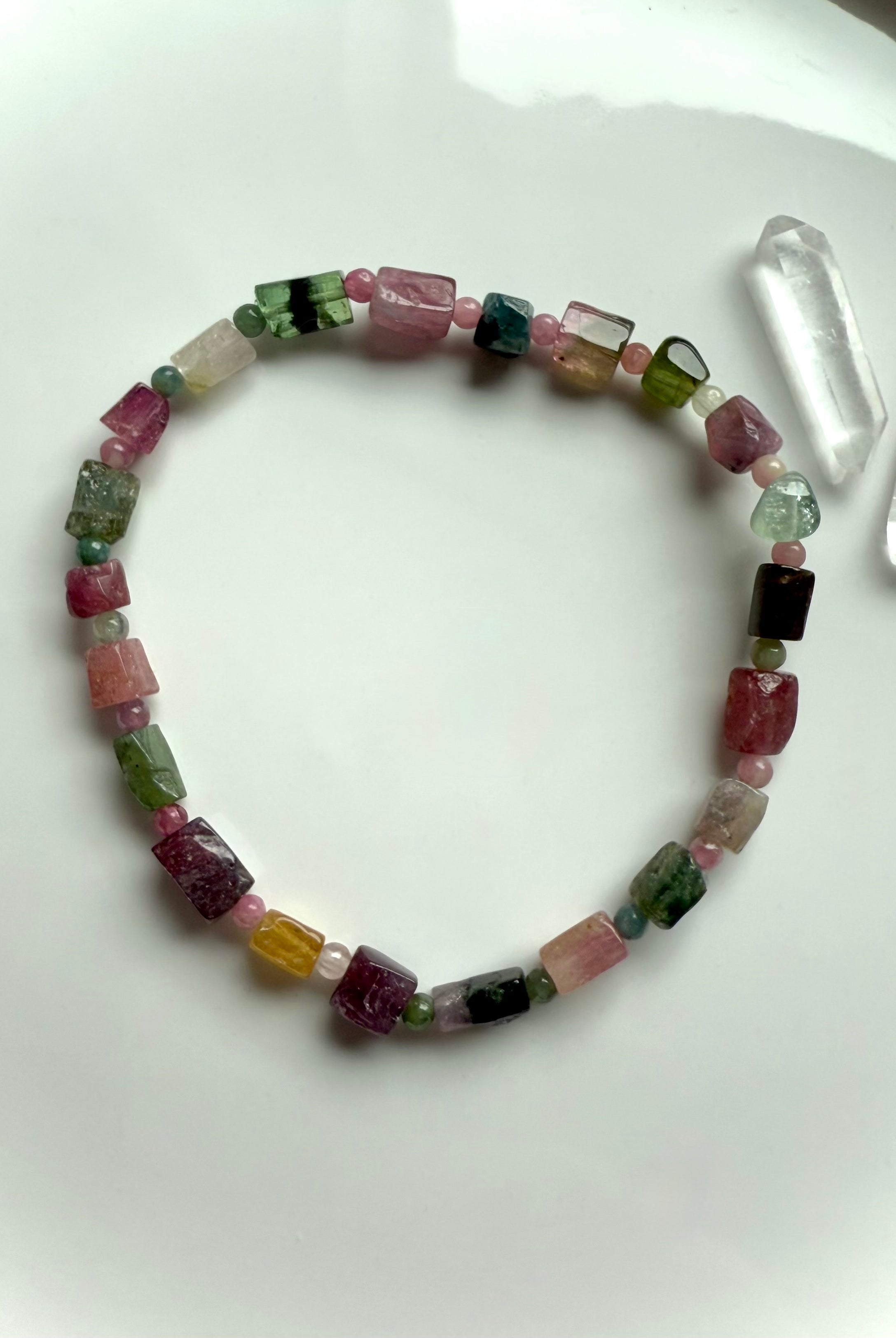 Our Rainbow Tourmaline Bracelet made with irregular cube shaped gems shown on a white plate