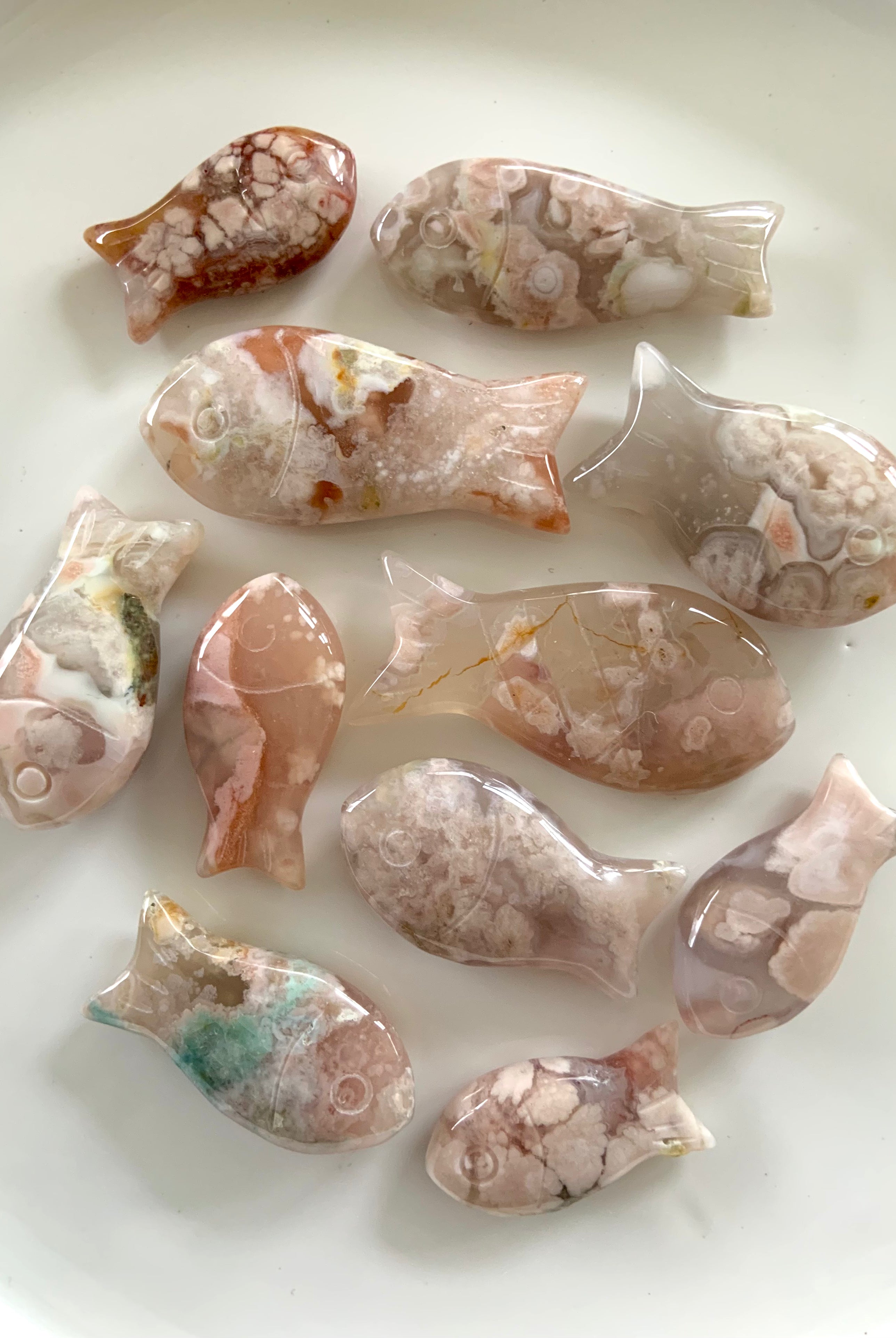 Flower Agate Fish carvings in a variety of sizes, hand carved crystal fish shown on a white plate