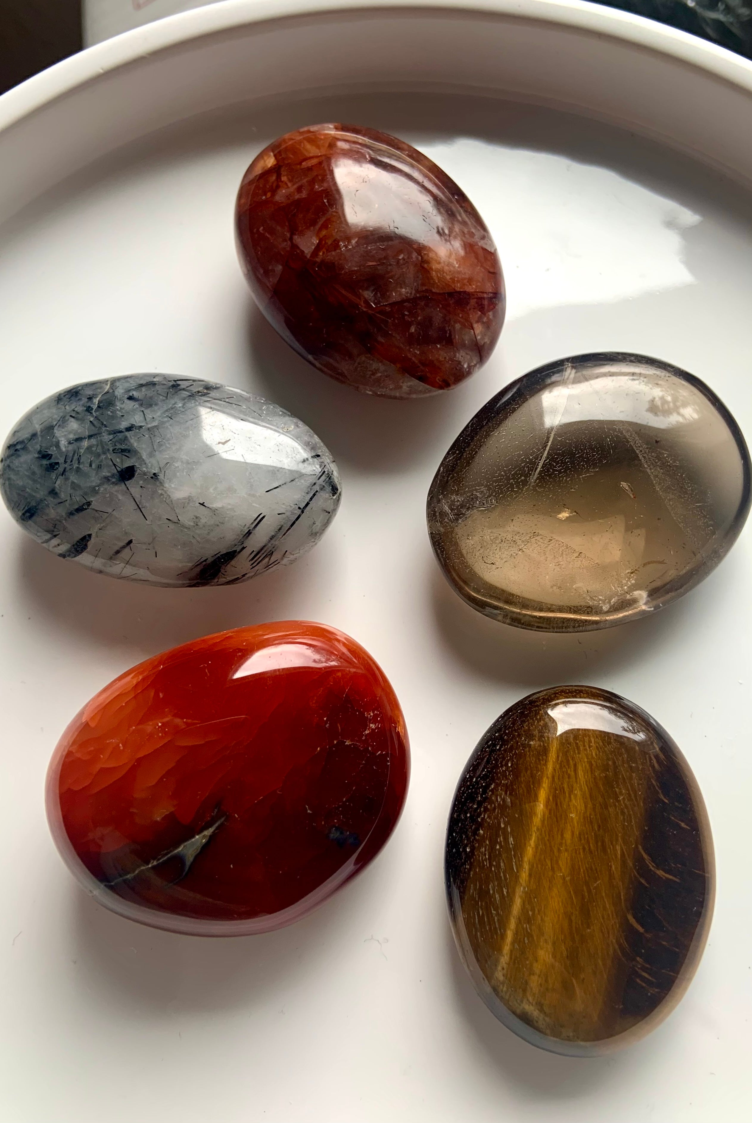 Polished palm stones on a white plate — crystal set for Root, Sacral & Solar Plexus chakra healing, motivation & energetic alignment.