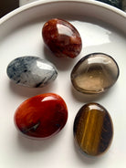 Polished palm stones on a white plate — crystal set for Root, Sacral & Solar Plexus chakra healing, motivation & energetic alignment.