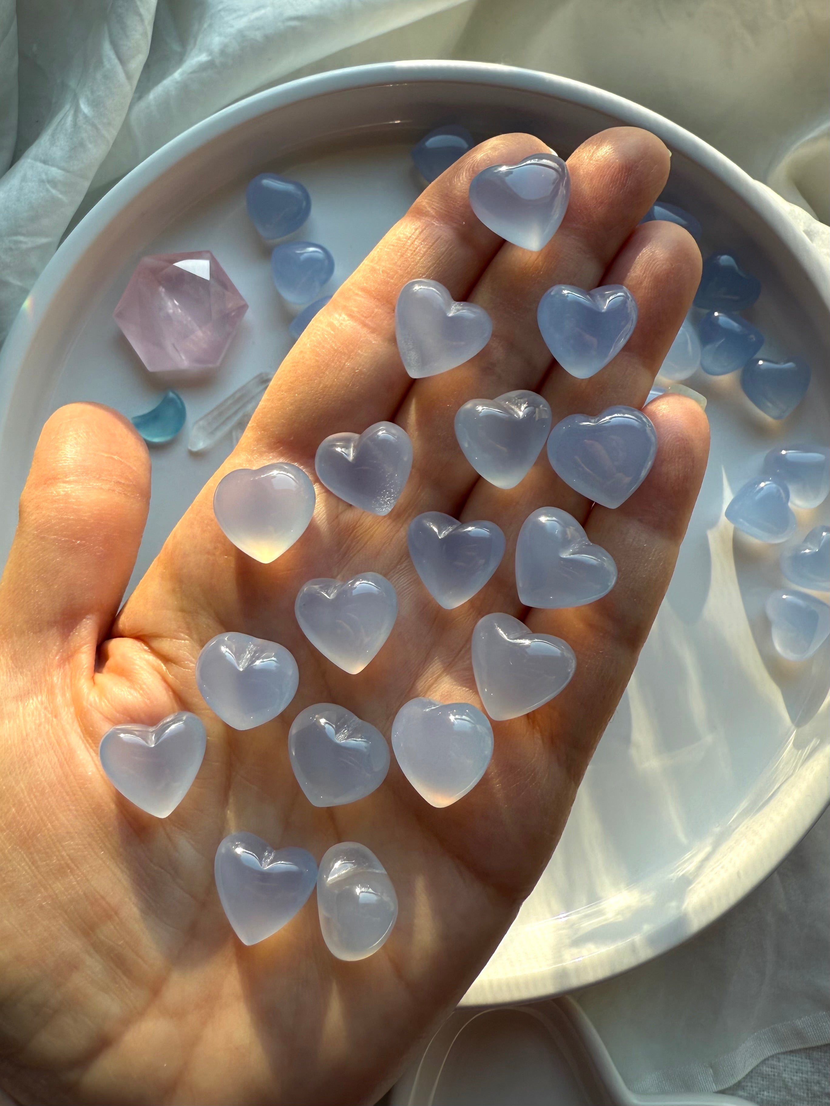 Mini Blue Chalcedony heart crystals held in hand to show size and smooth polish, small Throat Chakra stones for calm energy