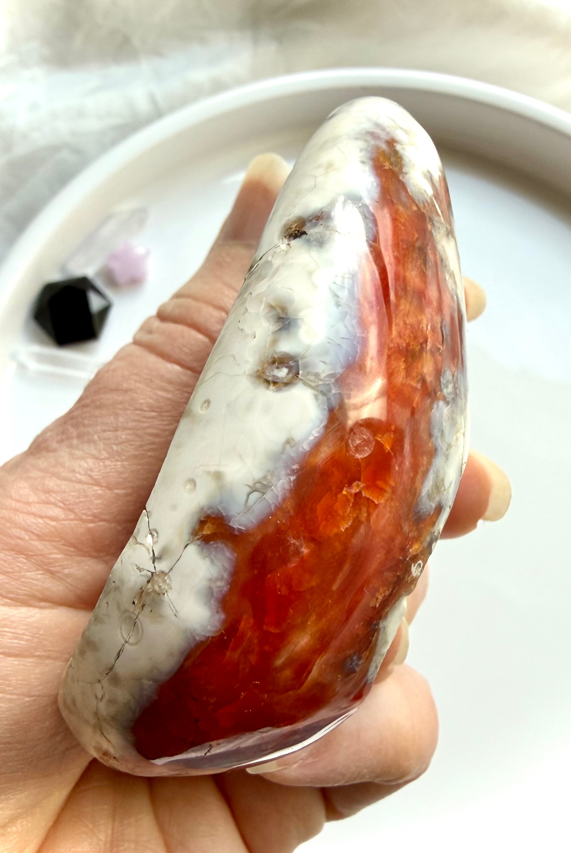 side view of polished carnelian bowl with orca agate pattern and translucent red orange tones