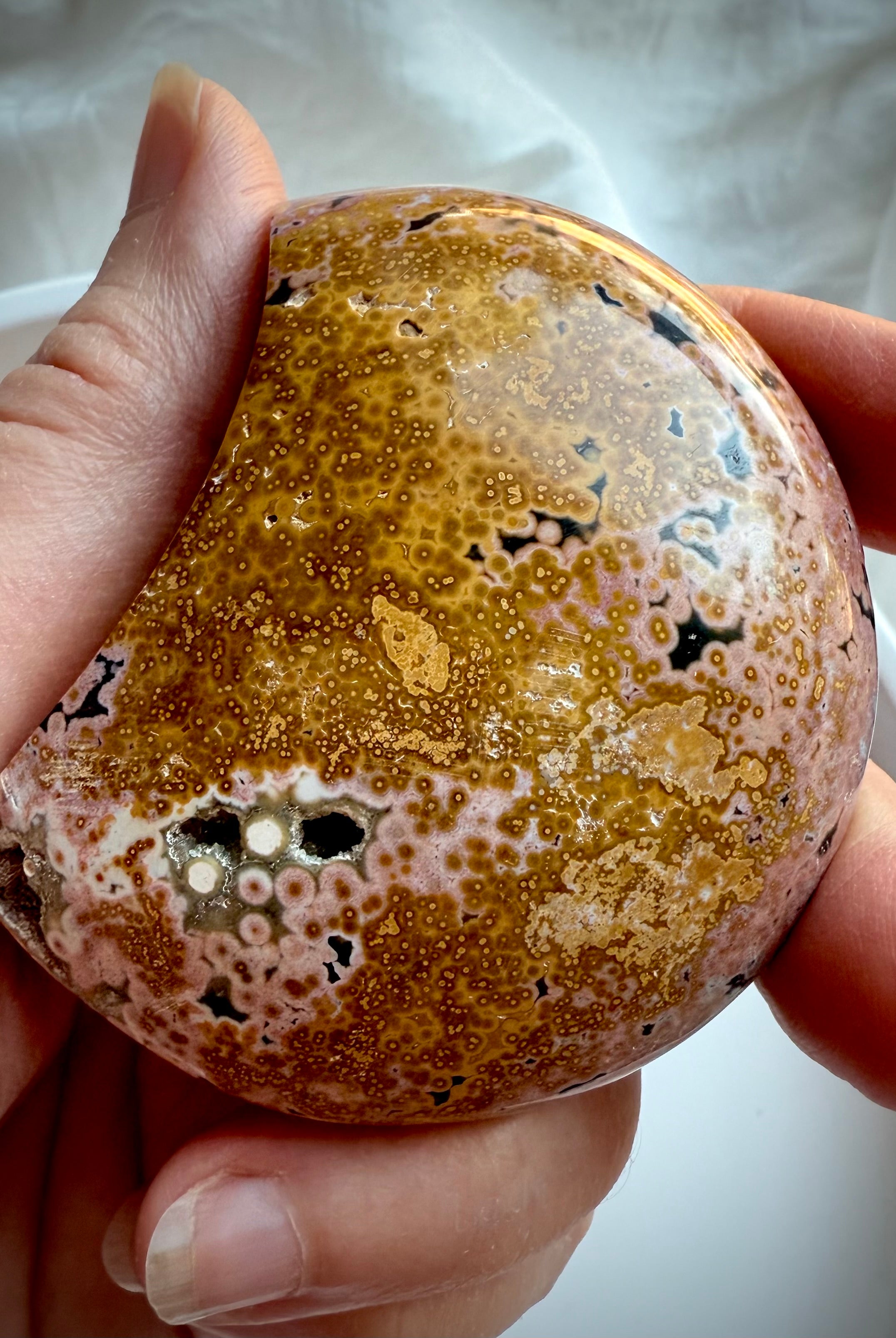 Peachy pink and yellow Ocean Jasper moon carving showing polished orbicular details and natural druzy accents
