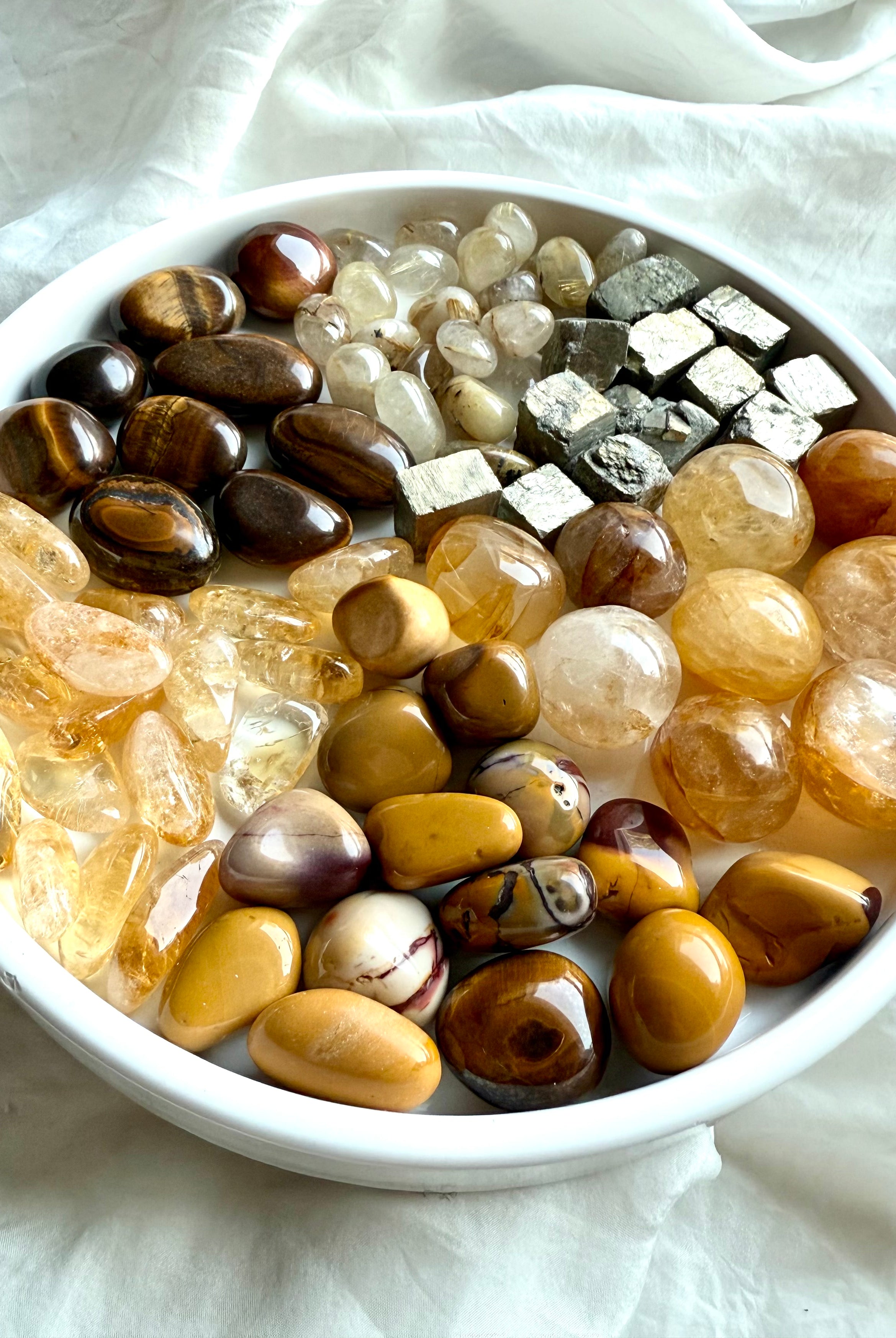Solar Plexus Chakra crystal set with golden healer, citrine, golden rutile, tiger’s eye, yellow mookaite, and raw pyrite crystals glowing on a white plate
